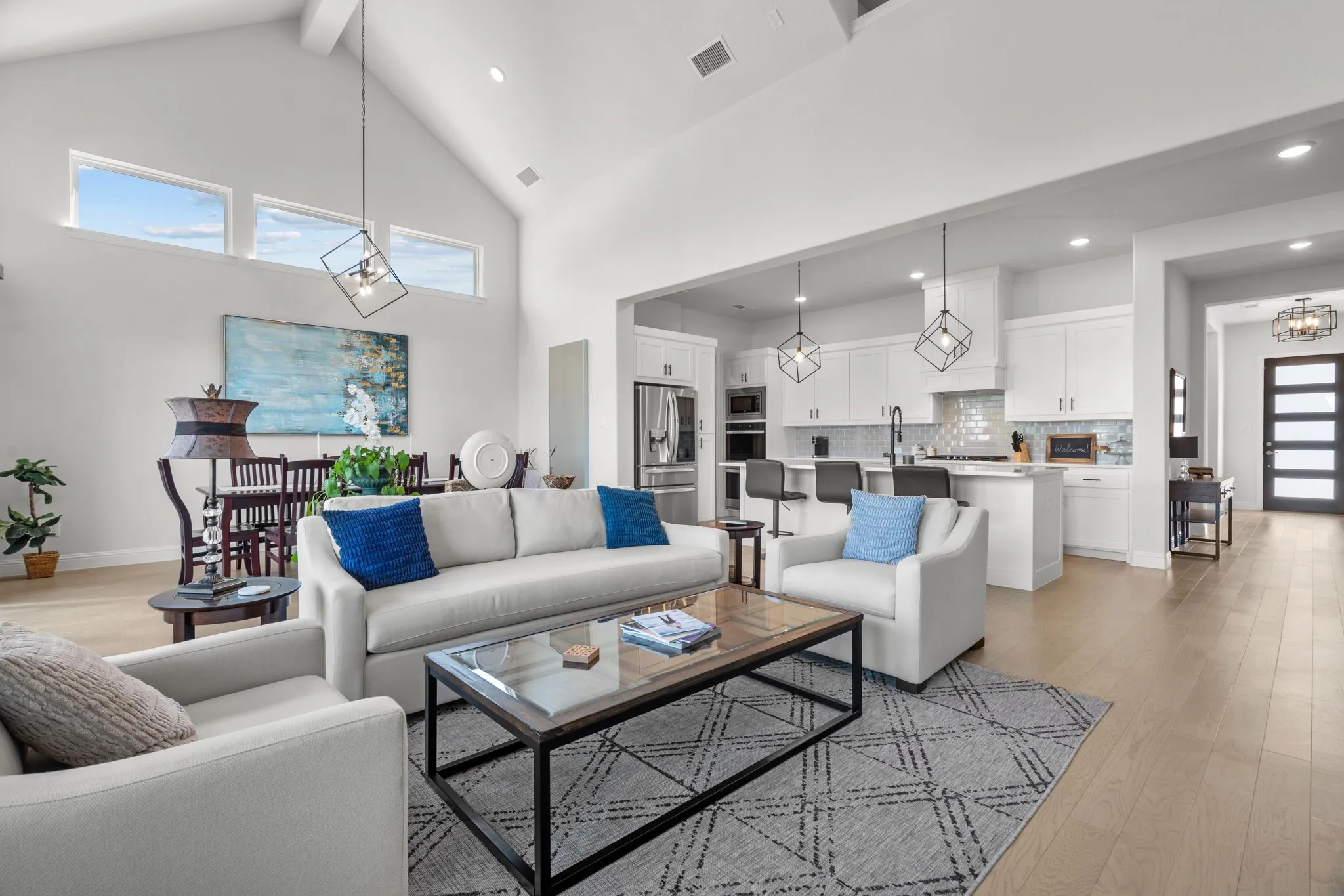 Open-concept living space featuring vaulted ceilings, light wood-finish flooring, and recessed lighting