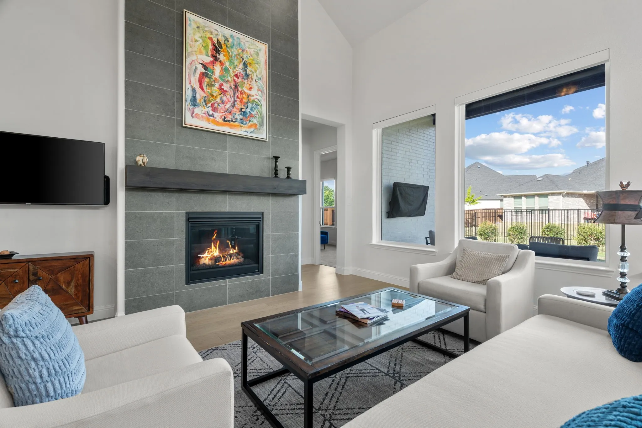 Living area featuring a floor-to-ceiling tile fireplace with a dark wood mantel, vaulted ceilings, and wood-finish flooring