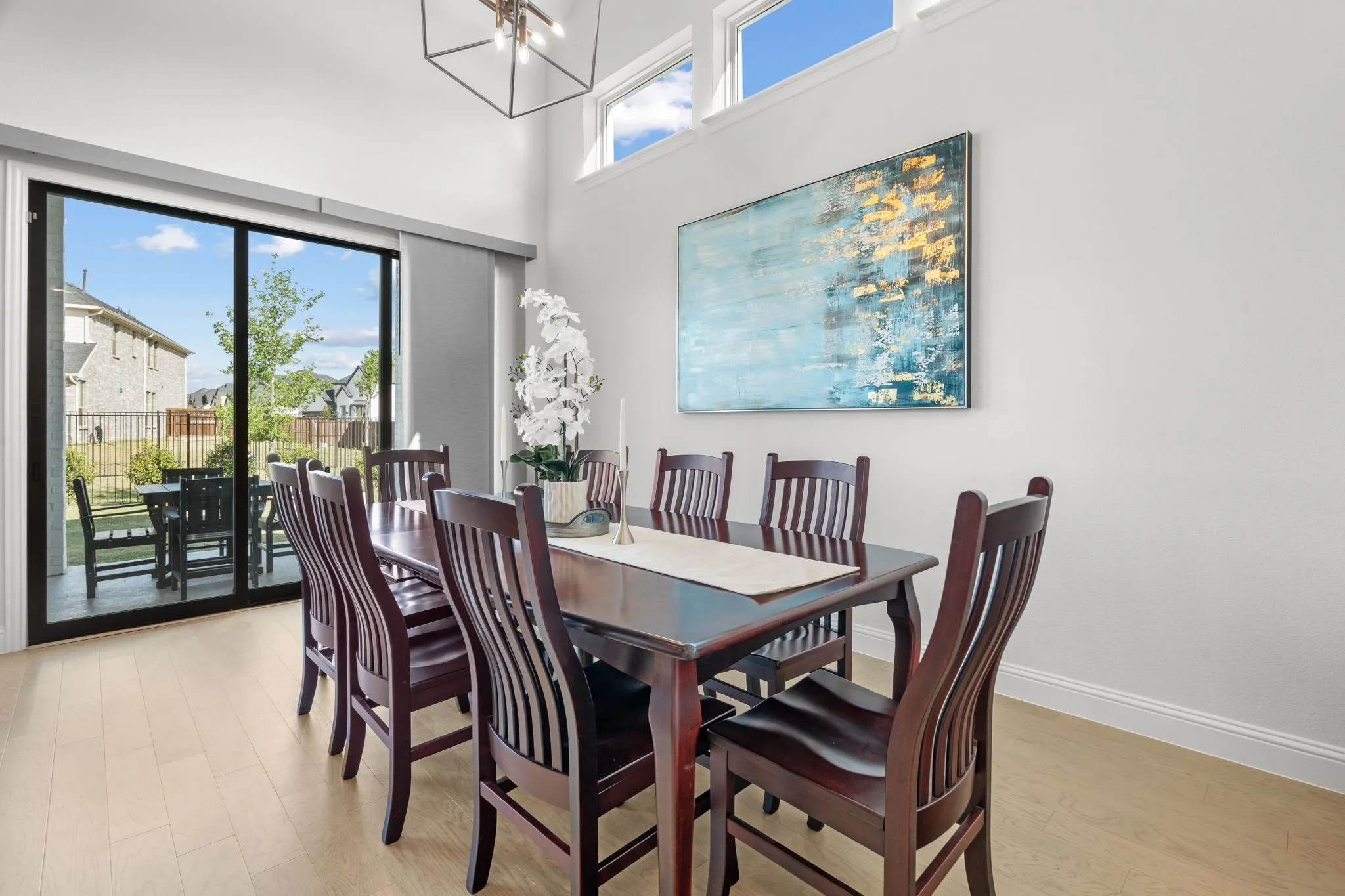 Bright dining area featuring light wood-finish flooring and a high ceiling