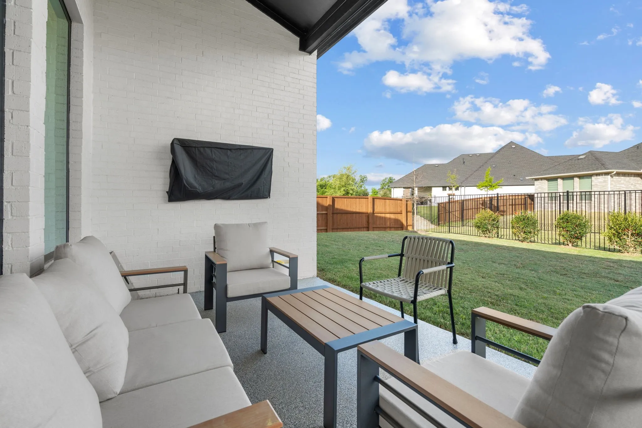 Covered patio featuring a white brick exterior, an expansive concrete surface, and a mounted fixture