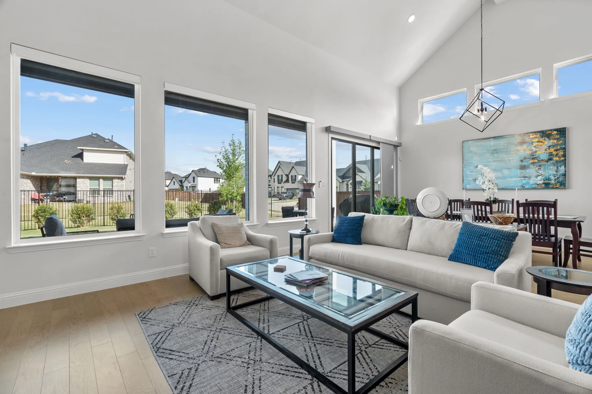 Open-concept living area featuring vaulted ceilings, abundant natural light from multiple windows, and wood-finish flooring