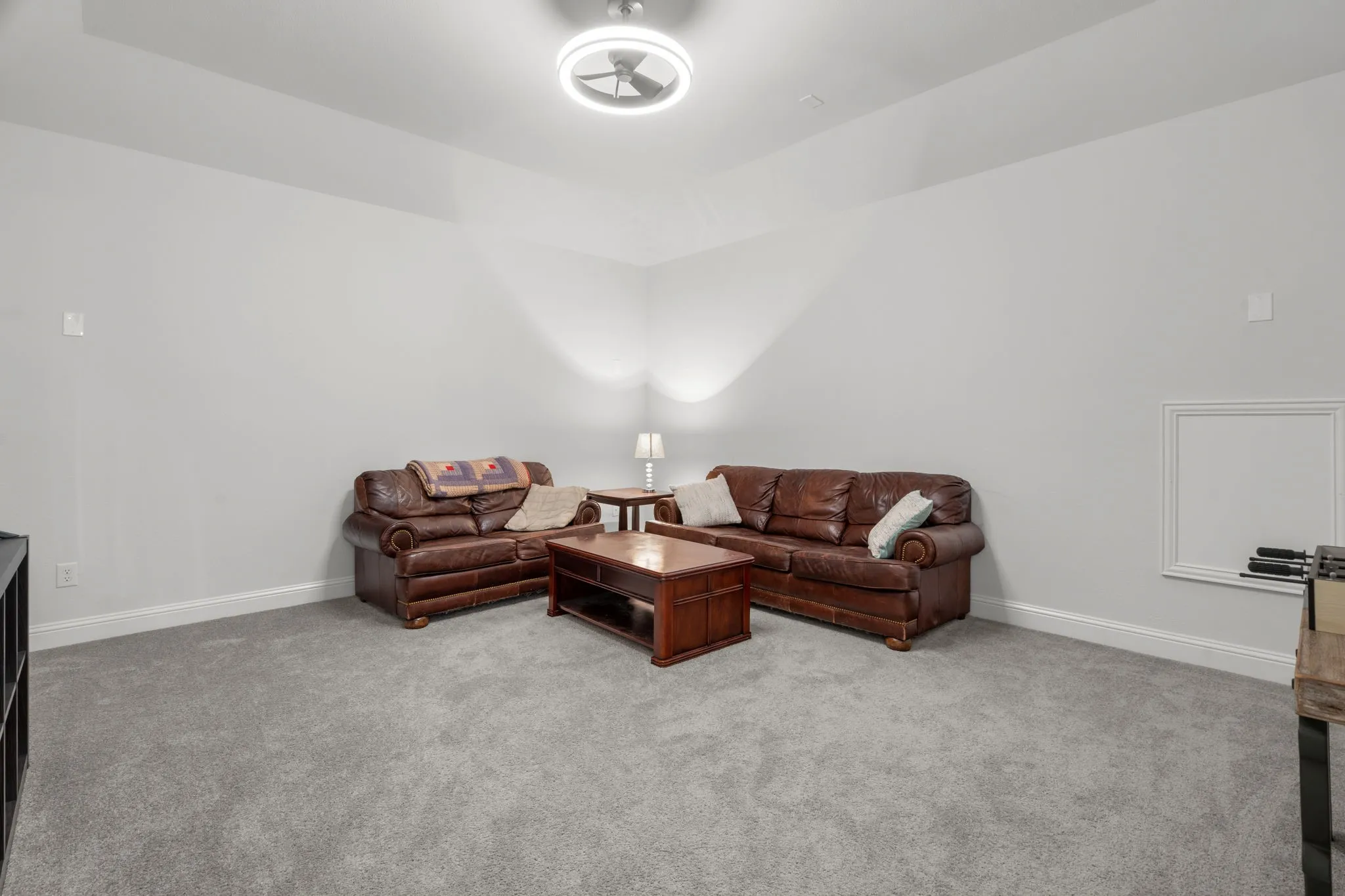 Carpeted living area featuring light gray walls, a sloped ceiling, and a ceiling fan with integrated lighting