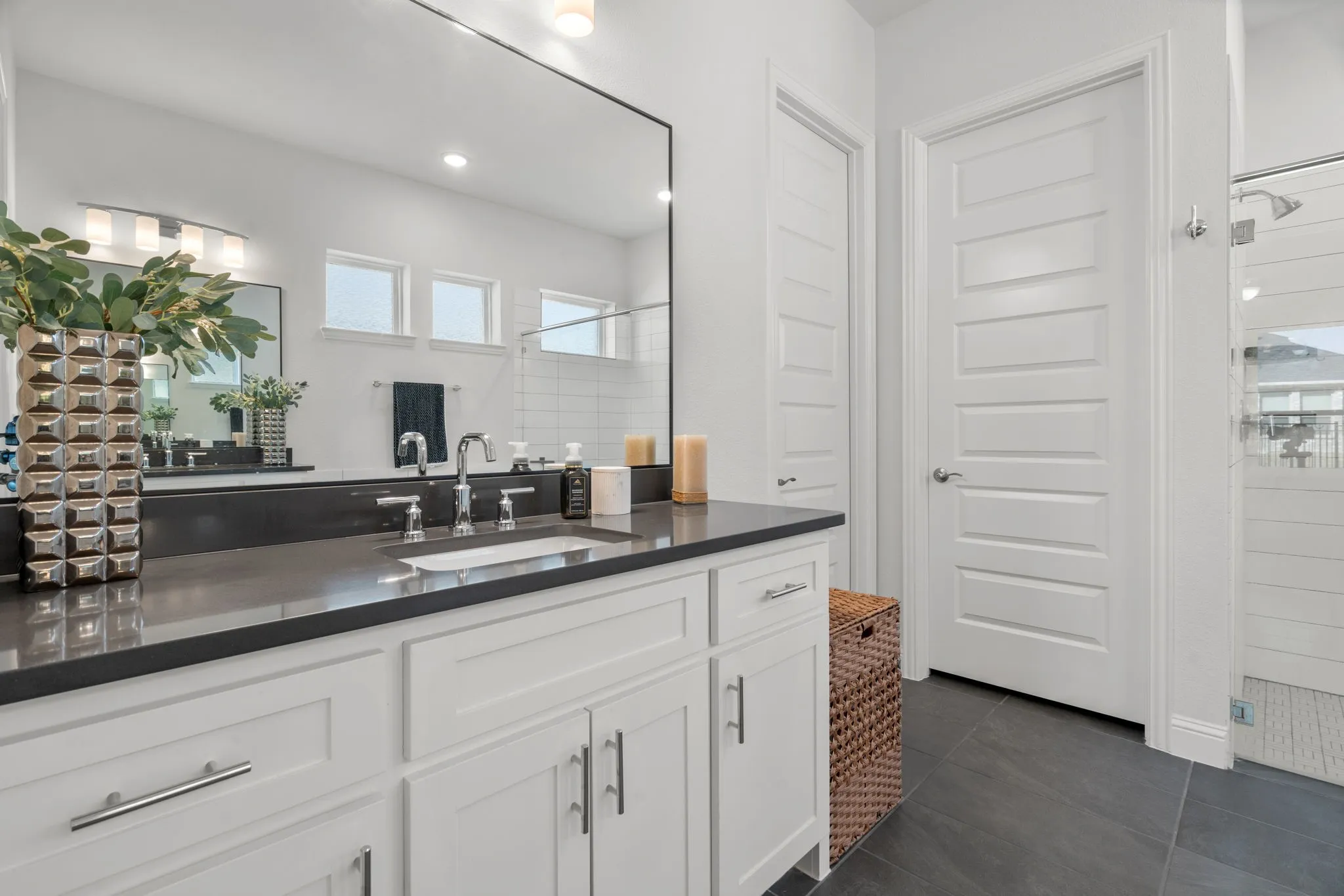 Bathroom featuring a white double vanity with a dark countertop, undermount sinks, and chrome faucets