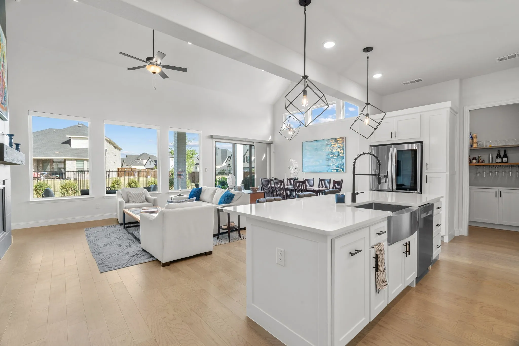 Open-concept interior featuring vaulted ceilings, light wood-finish flooring, and abundant natural light from multiple windows