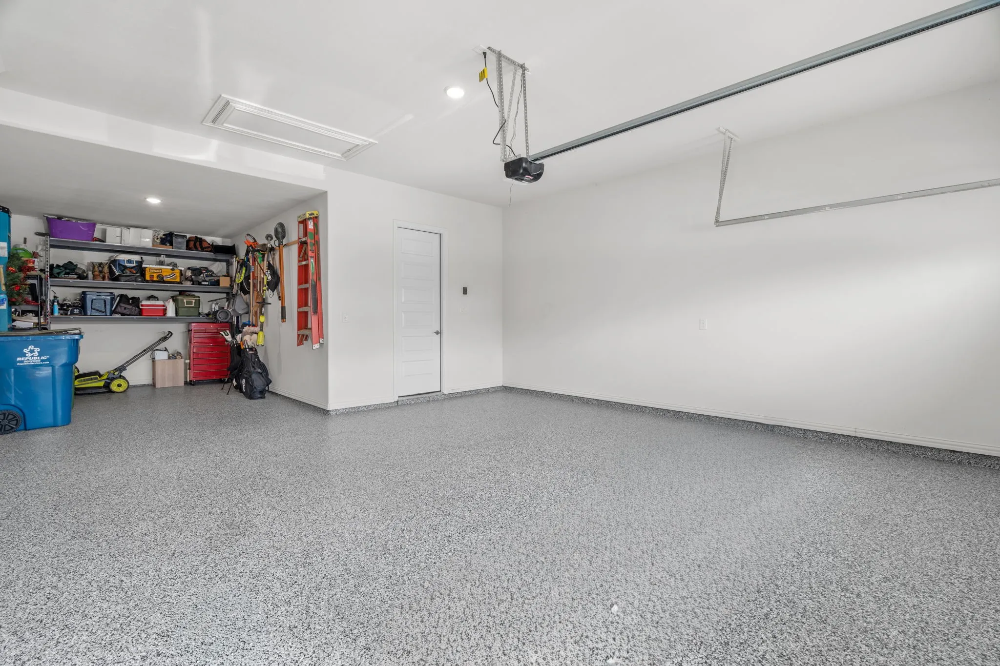 Spacious garage featuring a durable epoxy floor finish, white walls, and a single interior access door