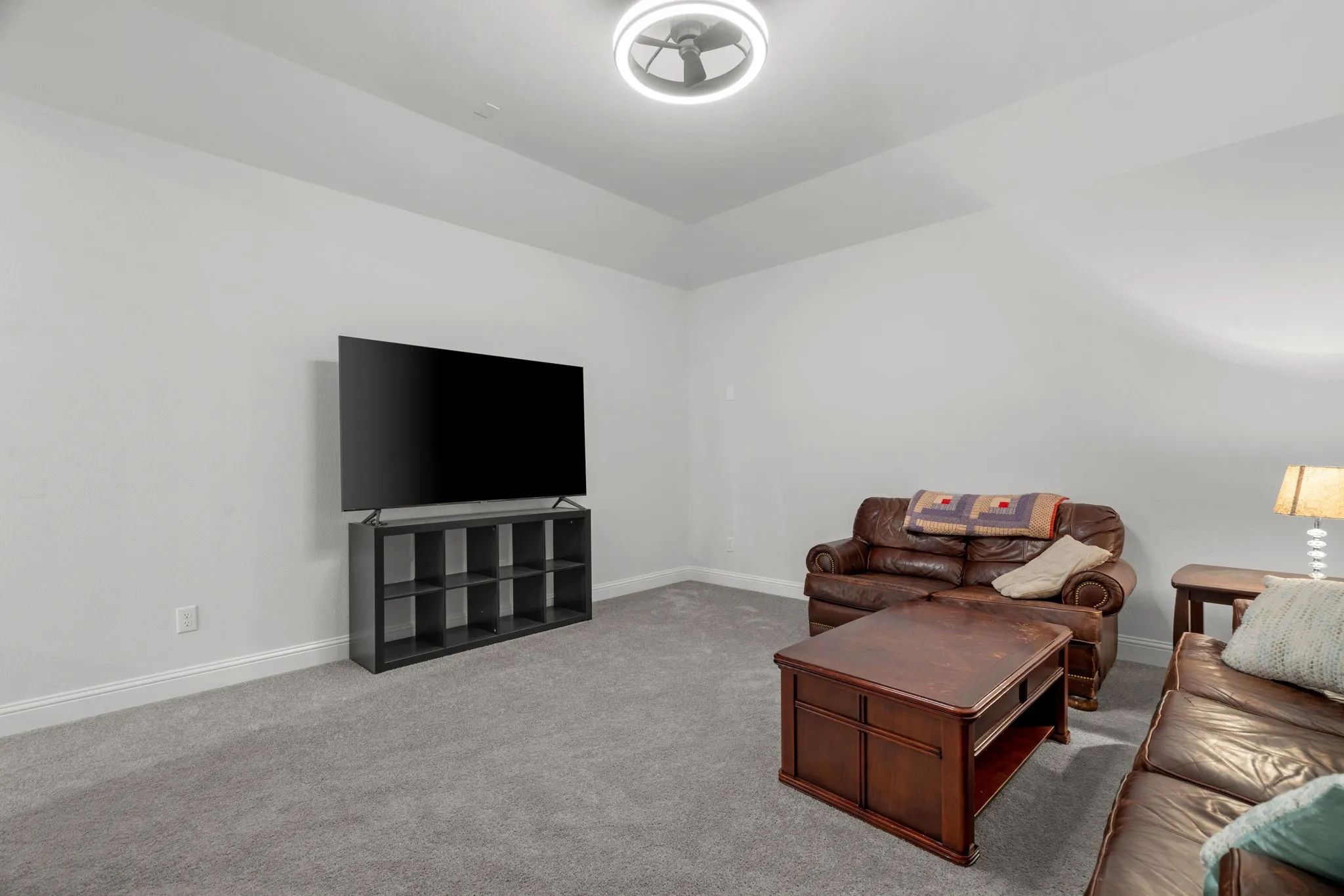 Spacious room featuring light gray carpeting, white baseboards, and neutral wall tones