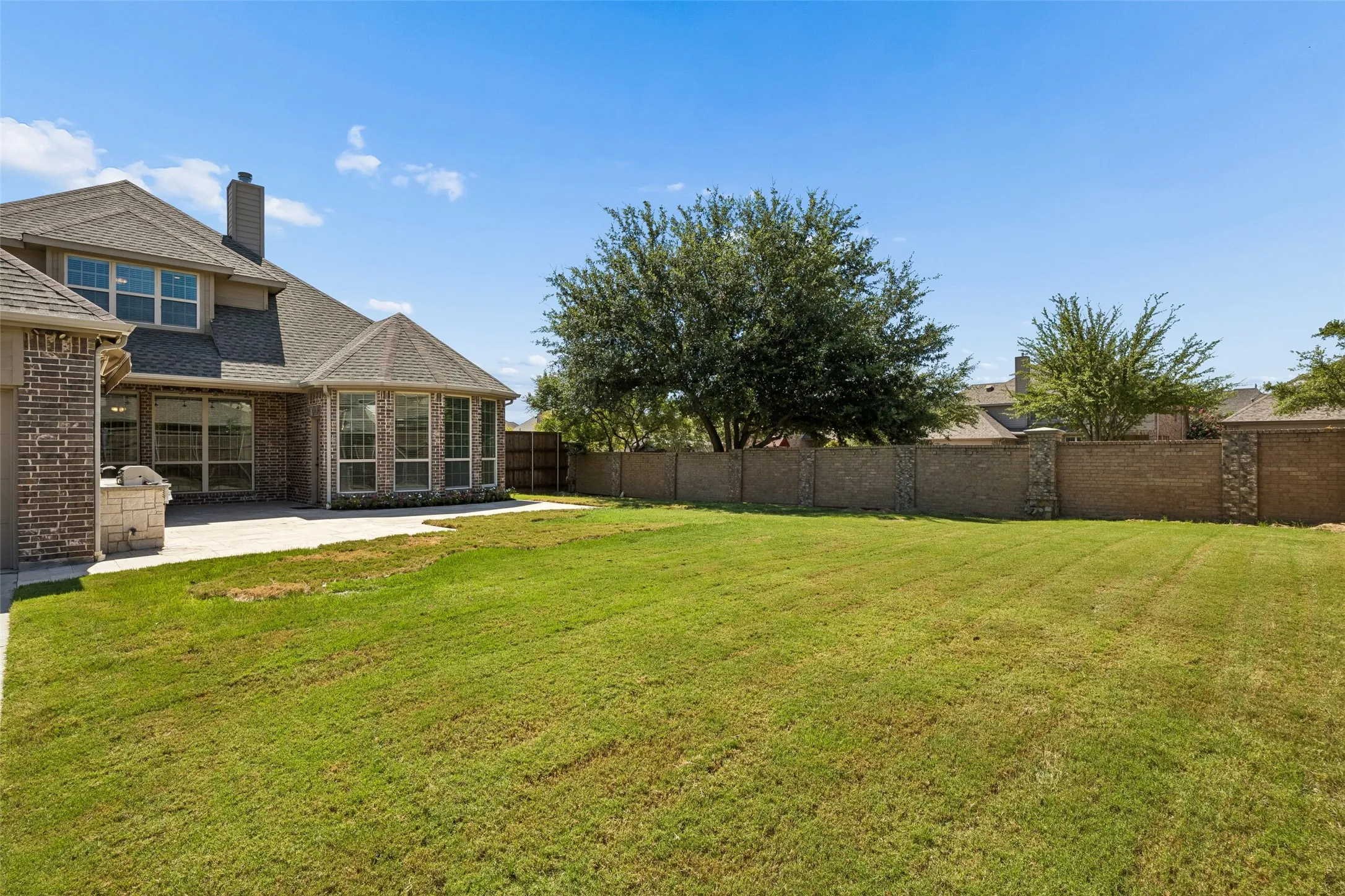 Expansive green lawn with a privacy wall