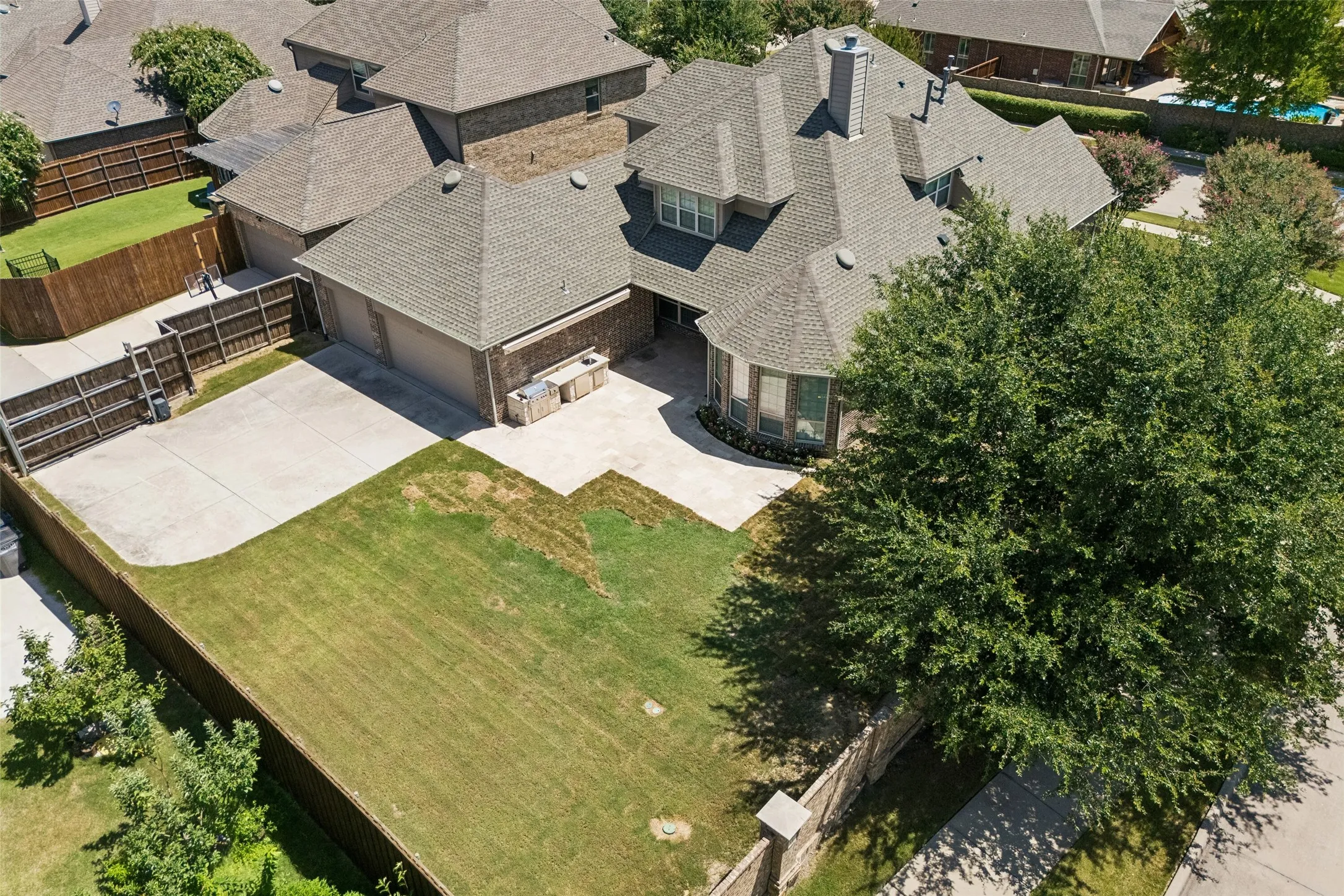 Expansive front yard featuring a mature tree, concrete driveway, and brick exterior