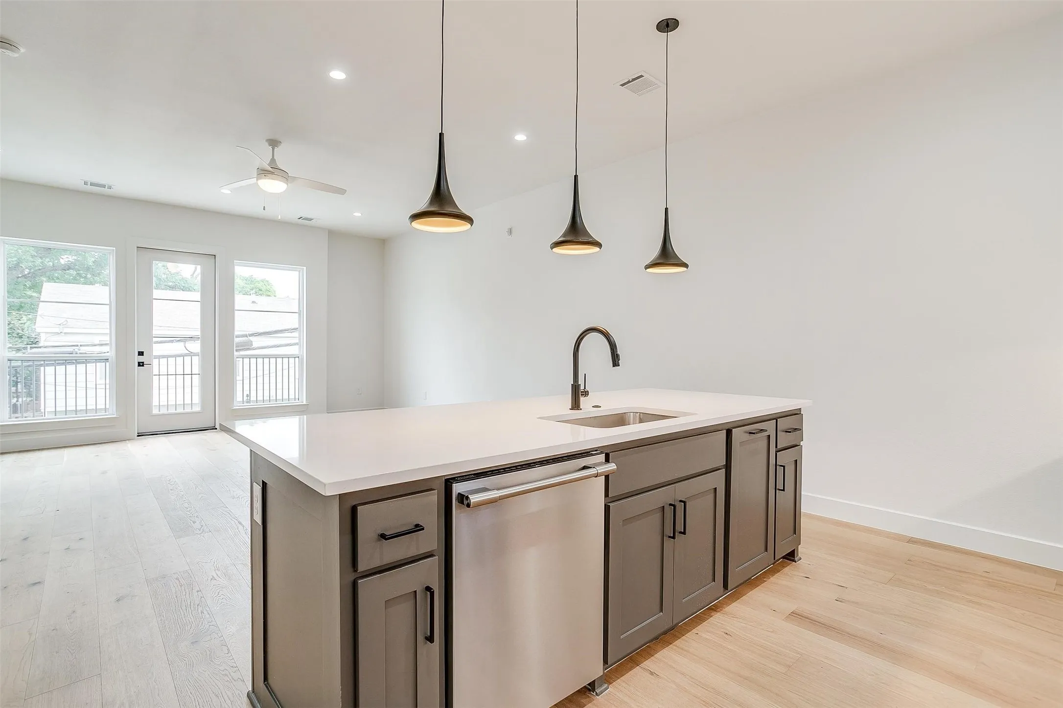 Kitchen featuring stainless steel dishwasher, a center island with sink, pendant lighting, light wood-type flooring, and recessed lighting