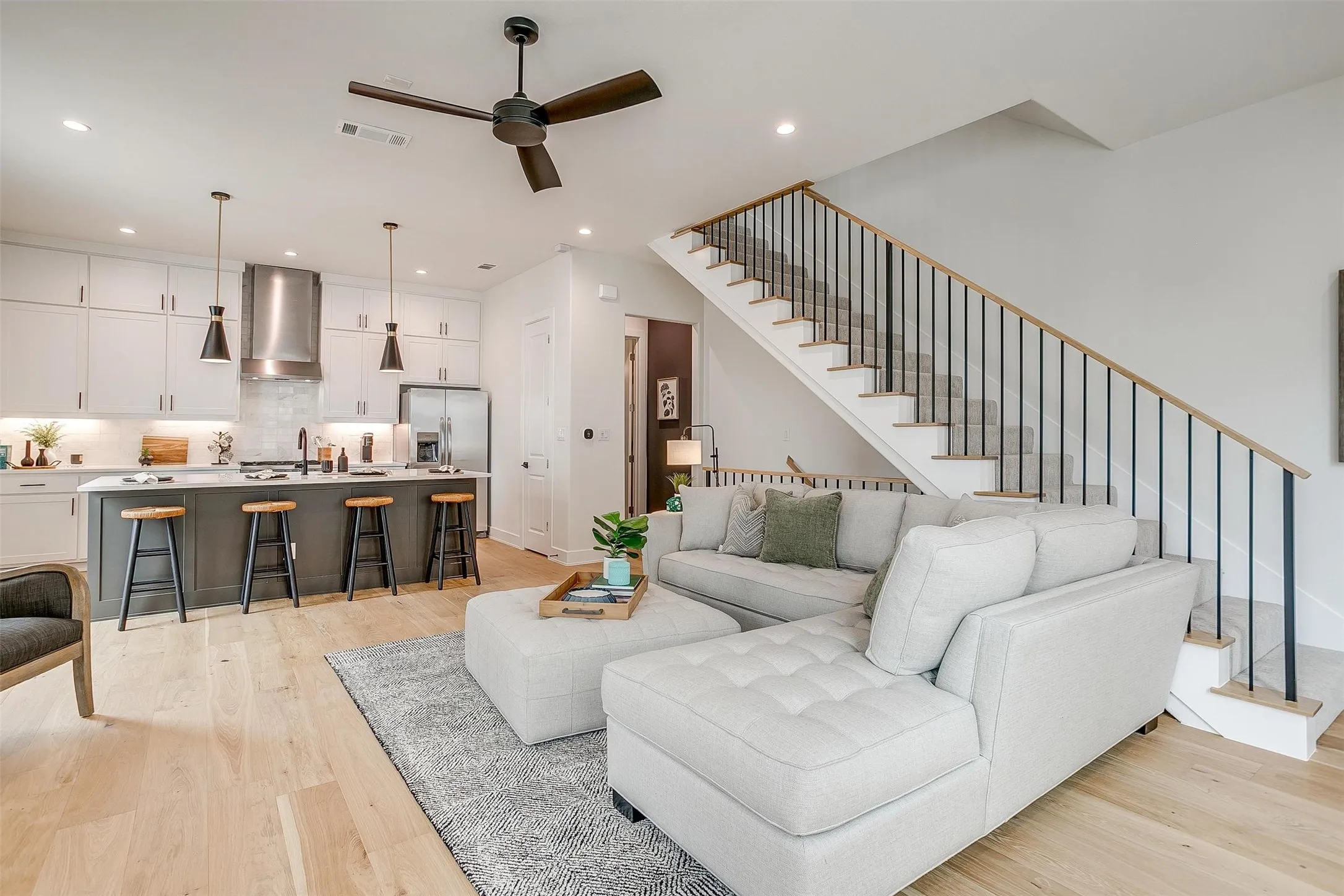 Living area with stairway, light wood-style flooring, ceiling fan, and recessed lighting