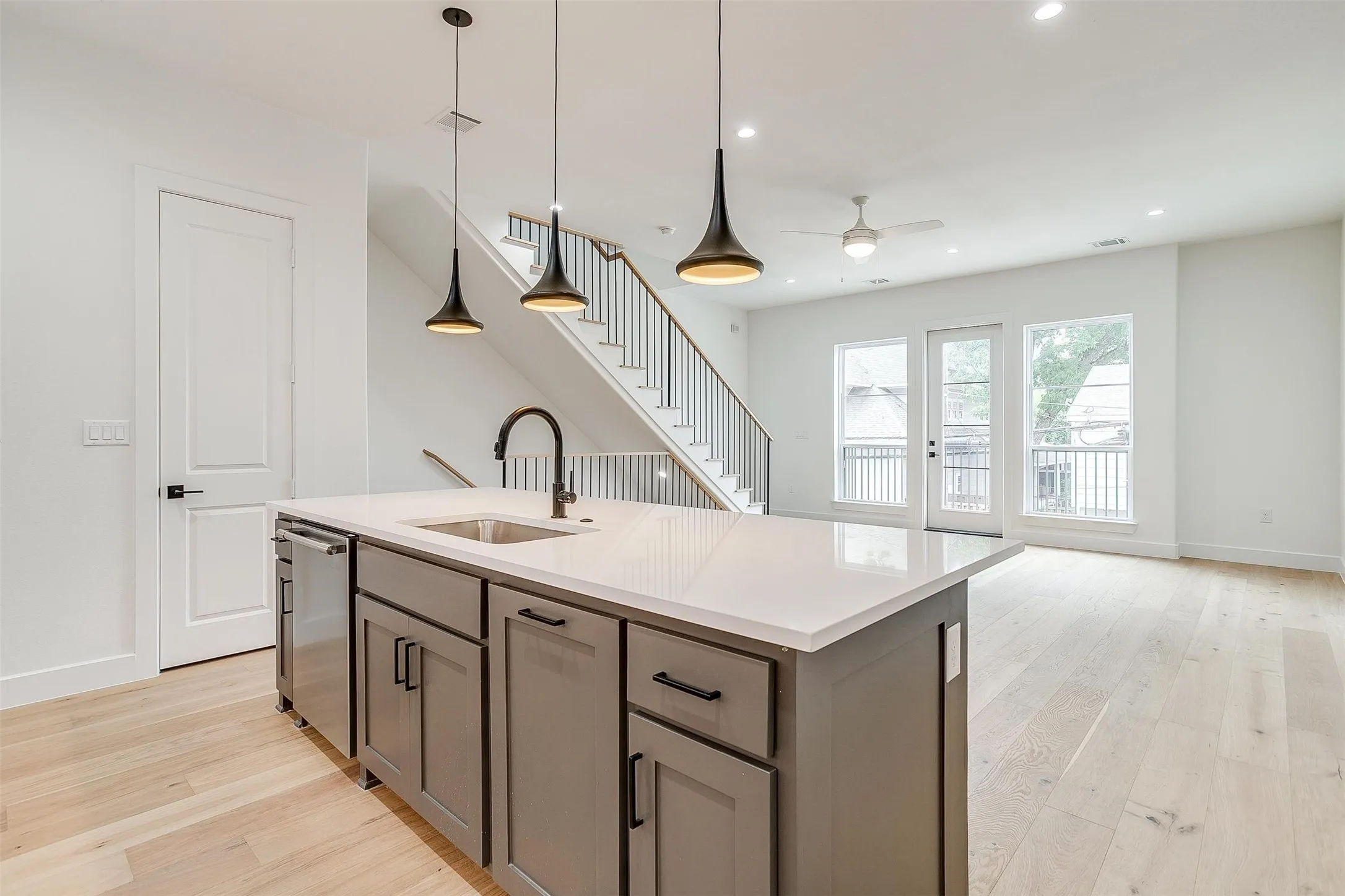 Kitchen with a kitchen island with sink, pendant lighting, light wood finished floors, recessed lighting, and light stone counters
