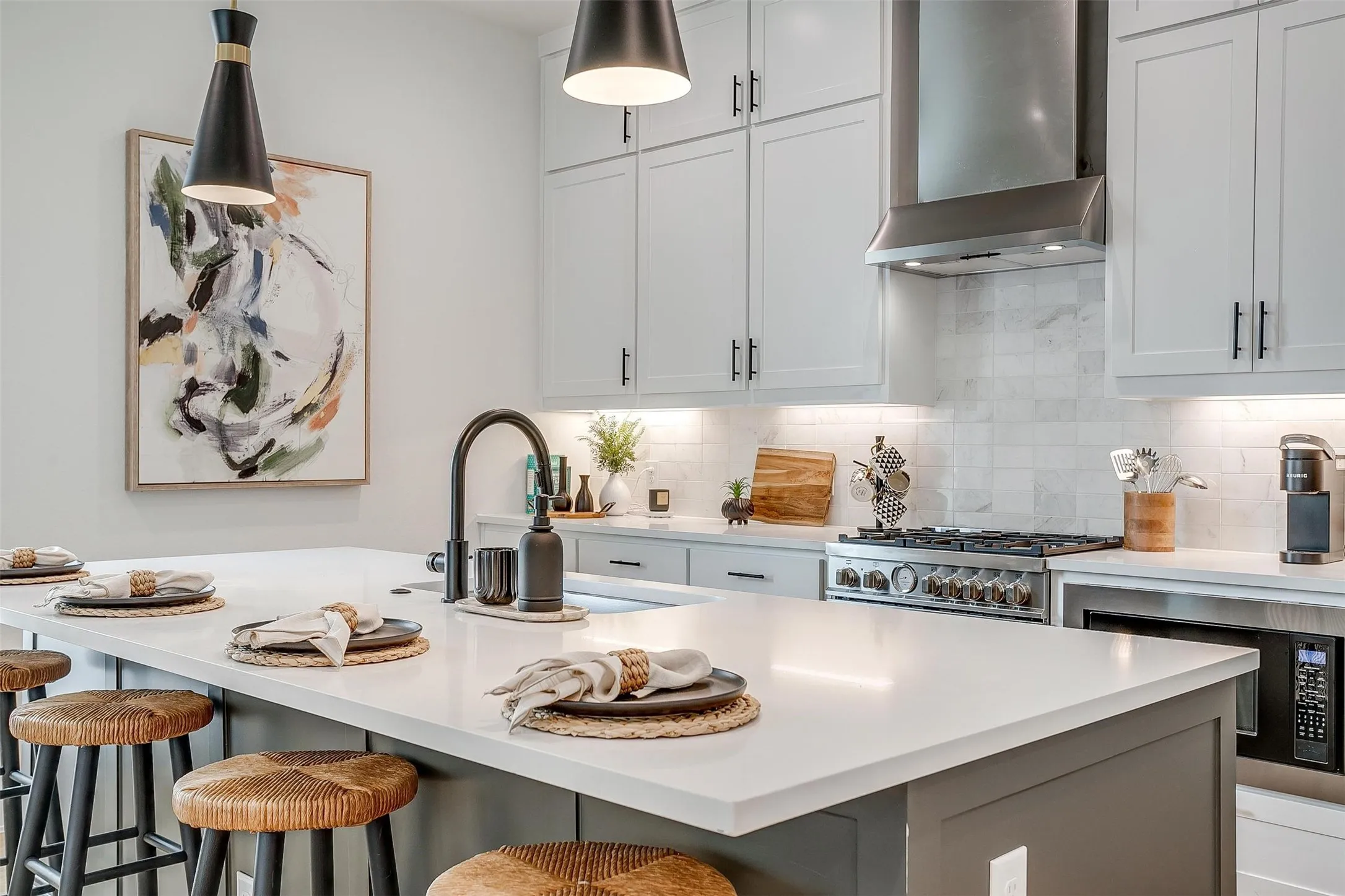 Kitchen featuring wall chimney exhaust hood, decorative backsplash, white cabinets, built in microwave, and stainless steel range with gas cooktop