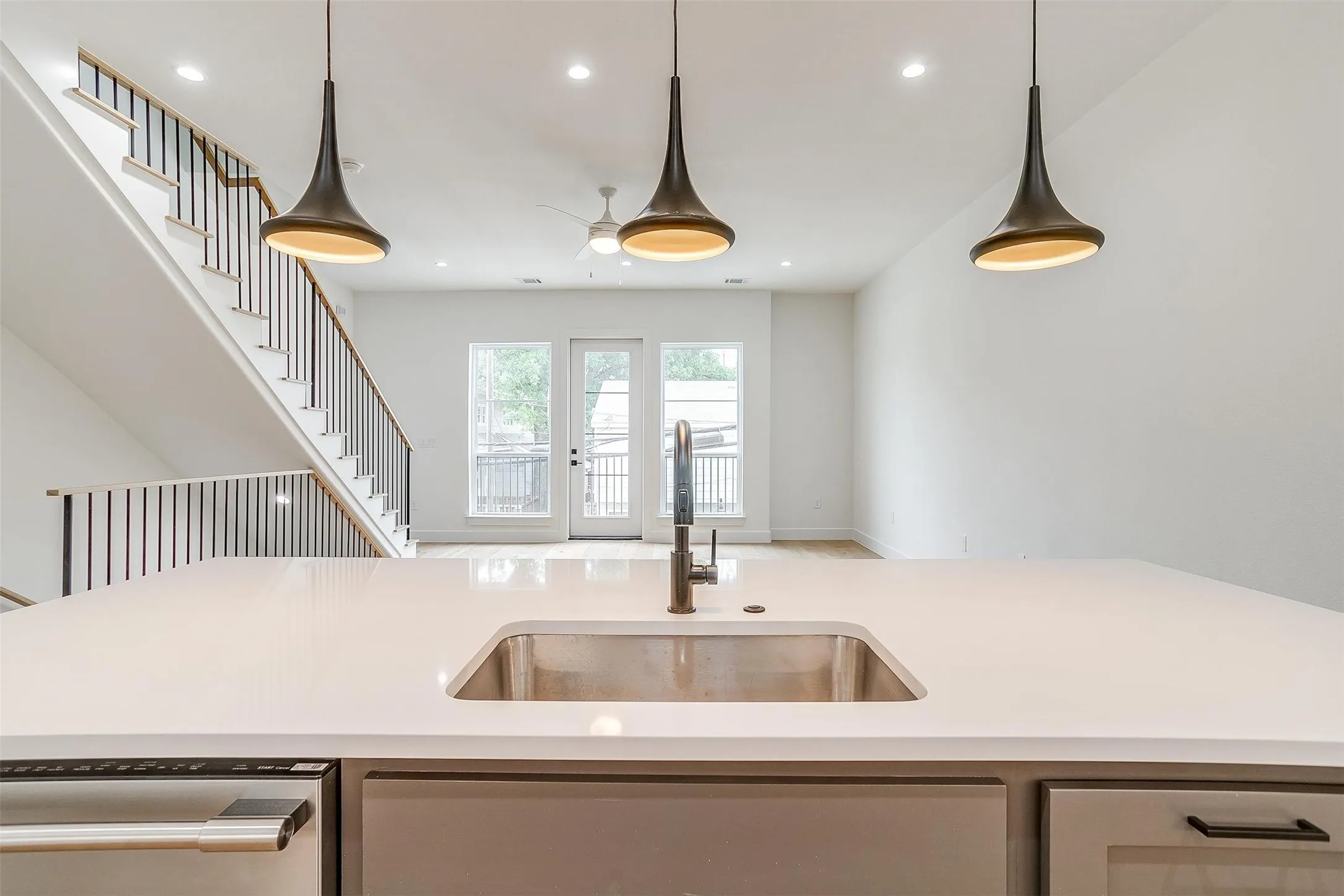 Kitchen featuring recessed lighting, stainless steel dishwasher, hanging light fixtures, light stone counters, and gray cabinets
