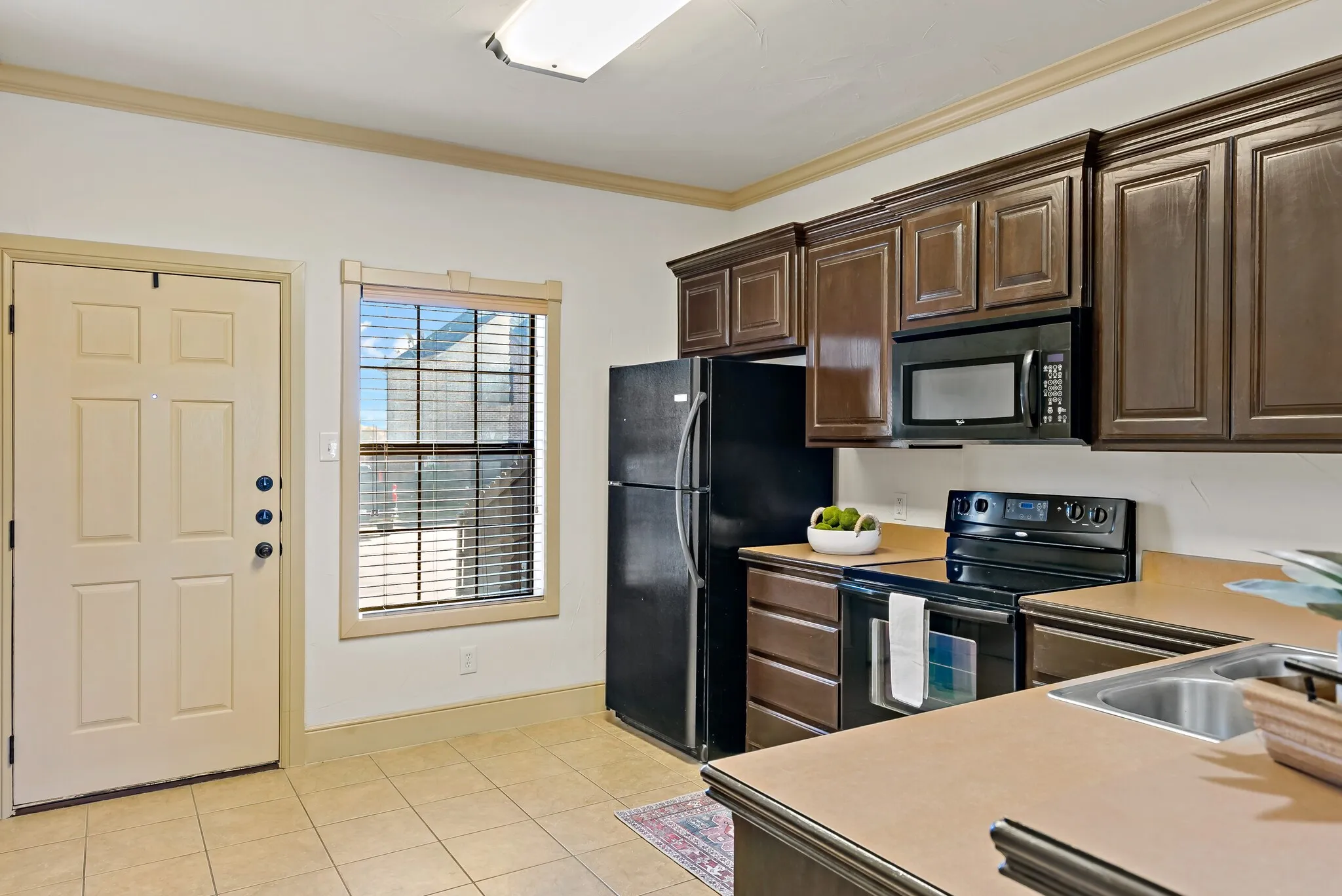 Kitchen featuring dark wood-finish cabinetry, black appliances, and a double basin sink