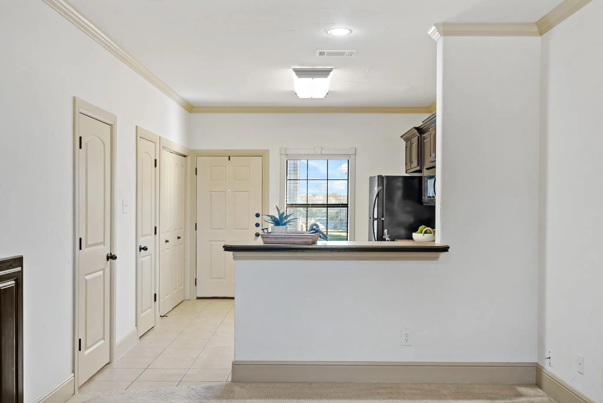 Kitchenette with dark wood-finish cabinetry and a black refrigerator