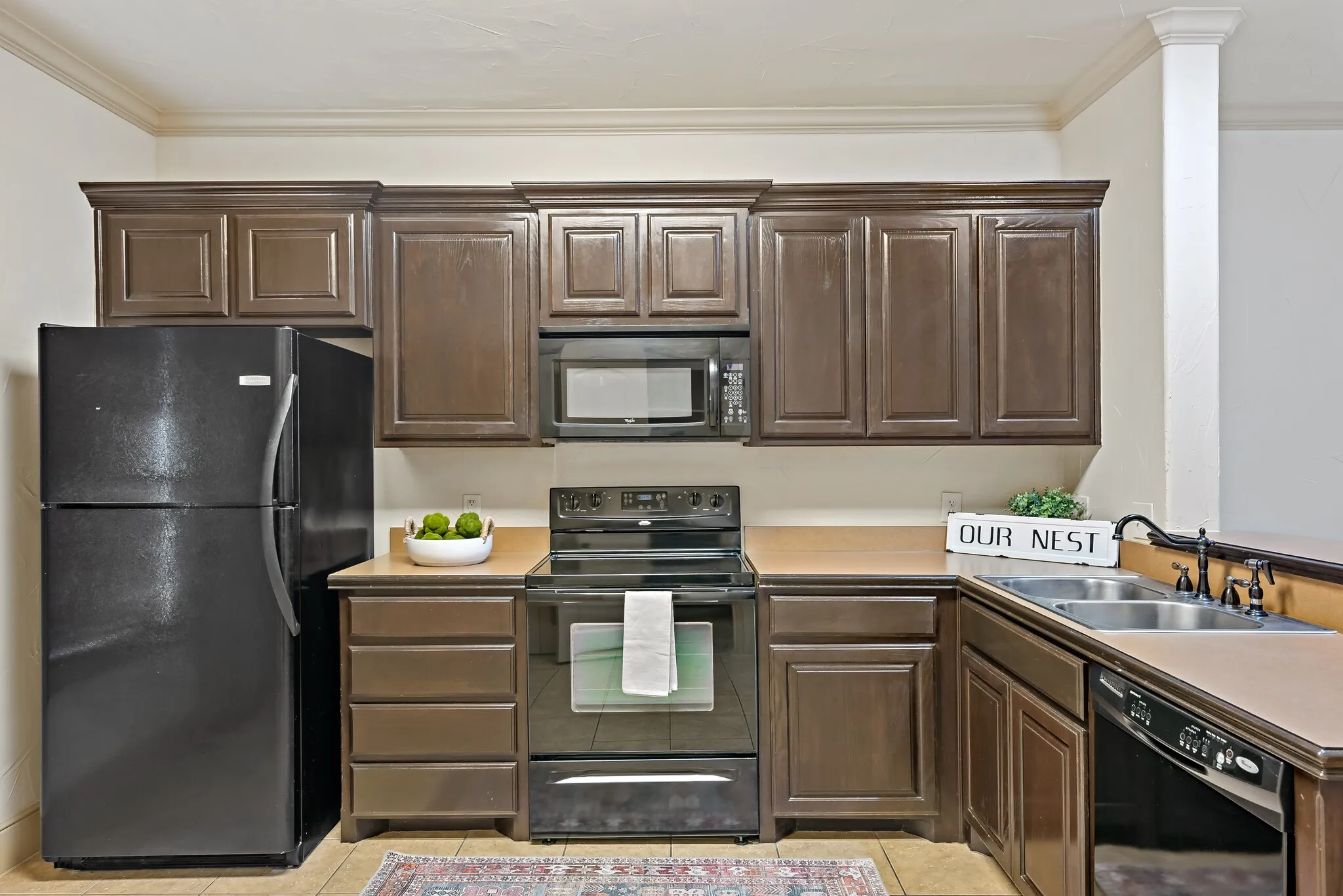 Kitchen featuring wood-finish cabinetry with crown molding, a black electric range, and a black microwave
