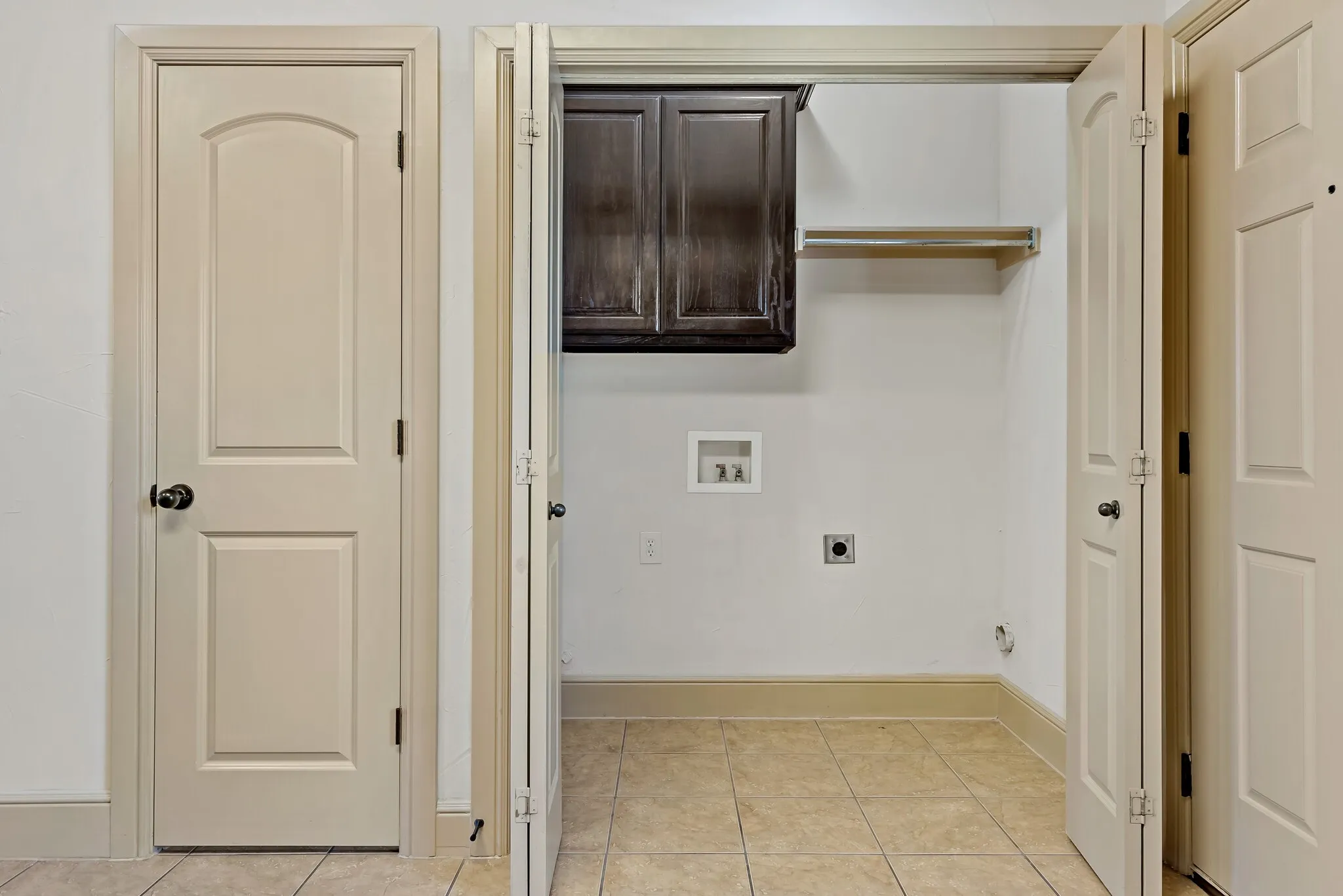 Dedicated utility area featuring tile flooring, a dark wood-finish wall cabinet, and a built-in shelf