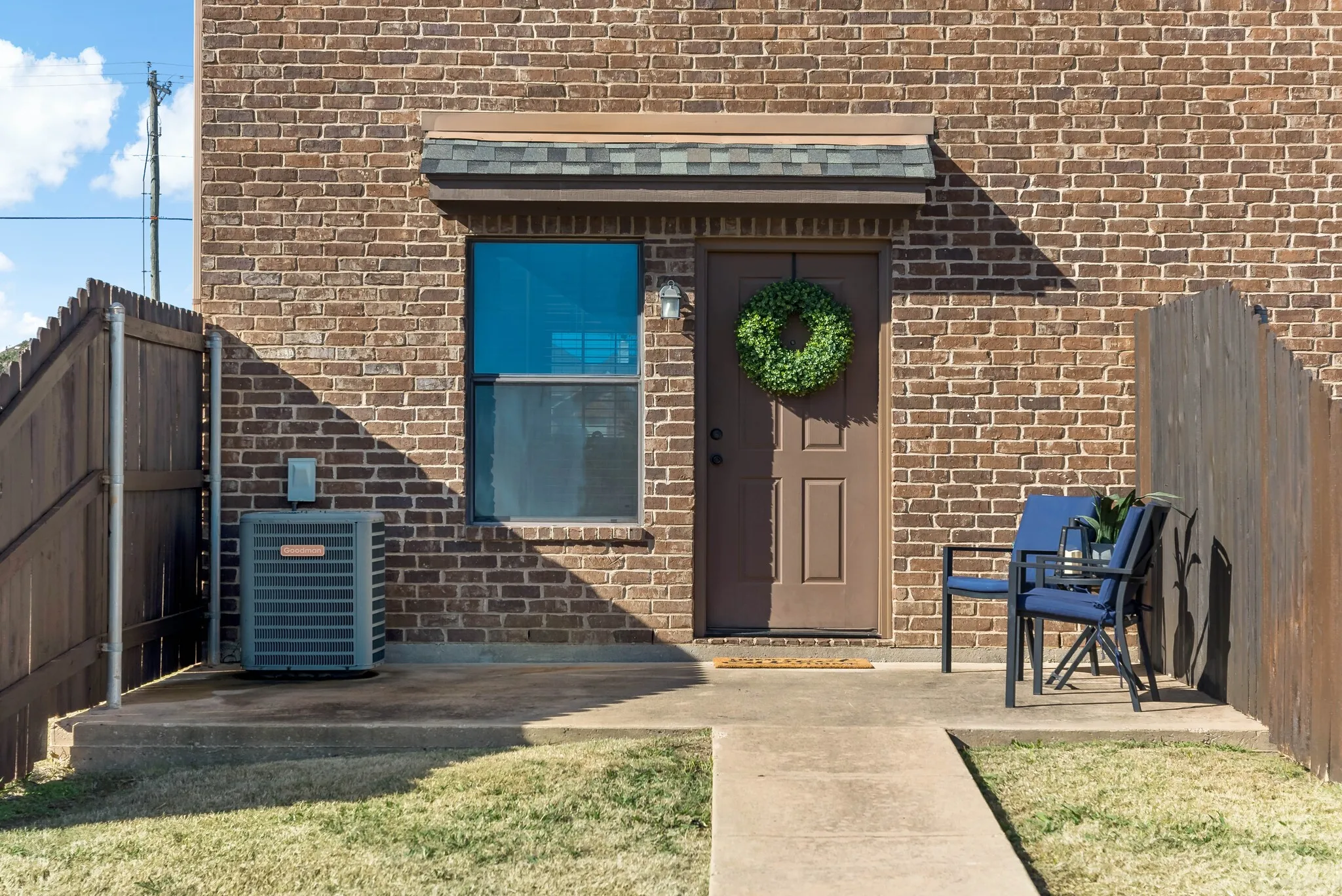 Brick exterior featuring a wood fence, concrete patio, and a covered entry door