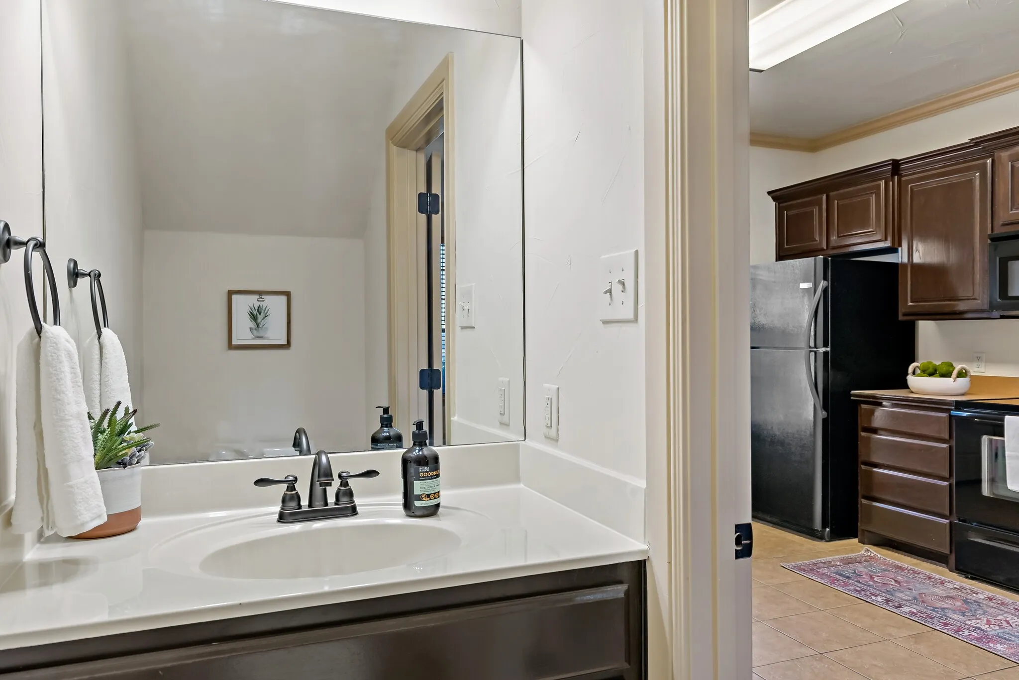 Bathroom vanity with an integrated sink, dark bronze-finish faucet, and a large wall-mounted mirror