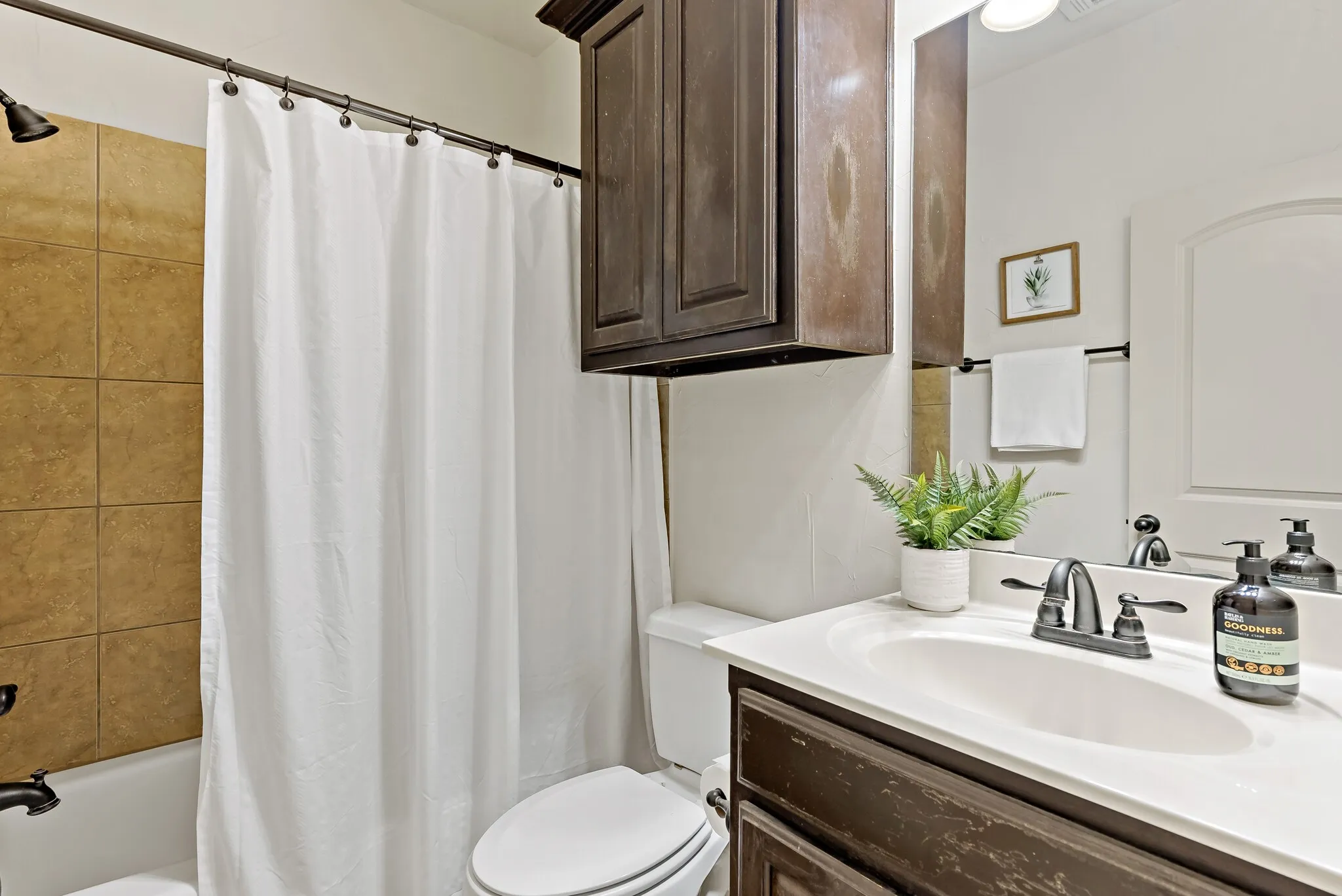 Bathroom featuring a shower-tub combination with large-format wall tiles, a built-in vanity with a white countertop, an undermount sink, and dark bronze-finish fixtures