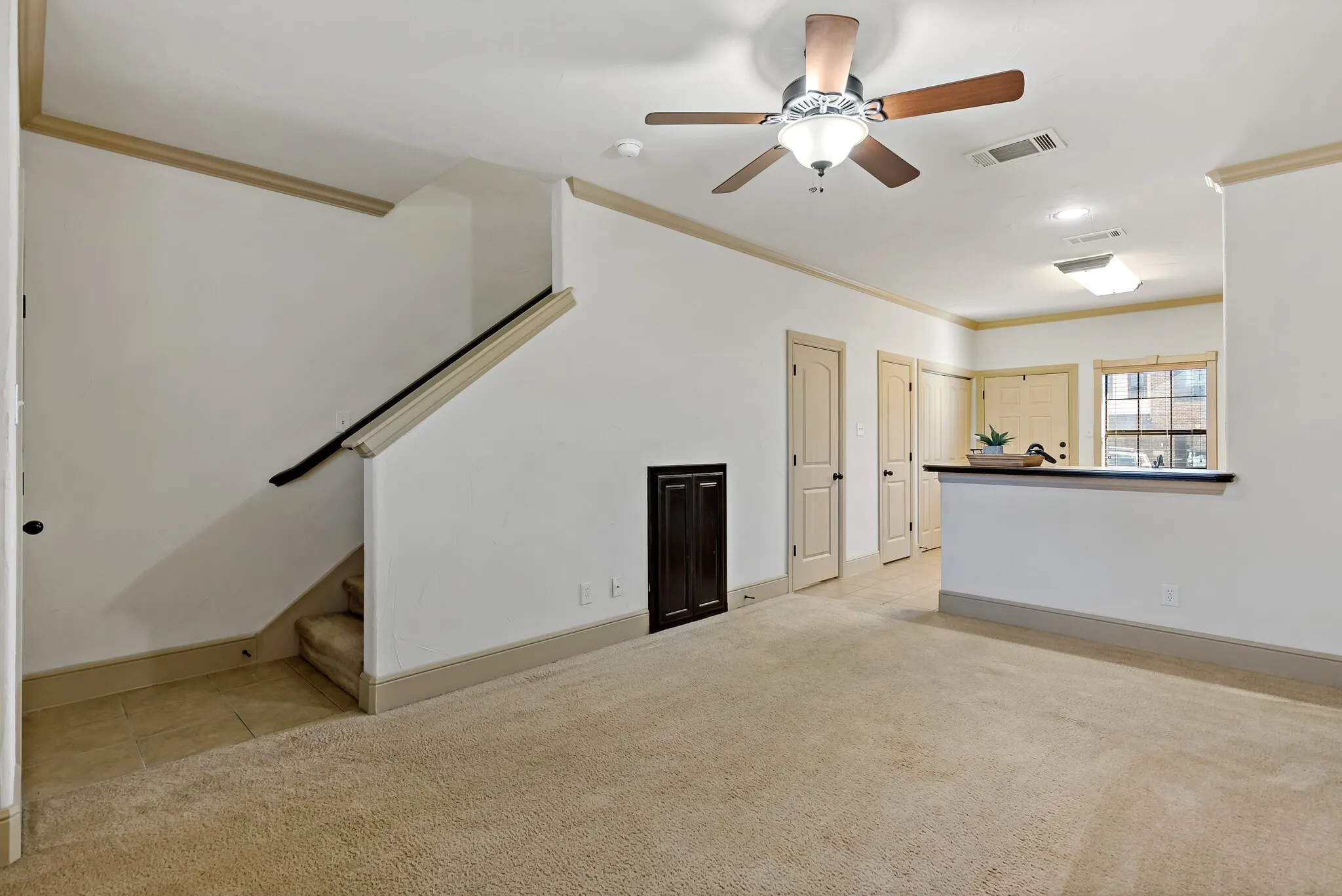 Carpeted living area with a ceiling fan, recessed lighting, and a partial wall with a dark countertop