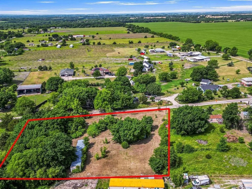 Expansive lot featuring mature trees and open land, bordered by green fields and residential properties