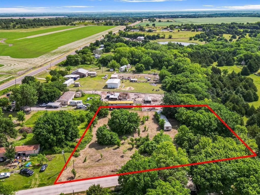 Expansive lot defined by a red outline, featuring mature trees and a partial clearing