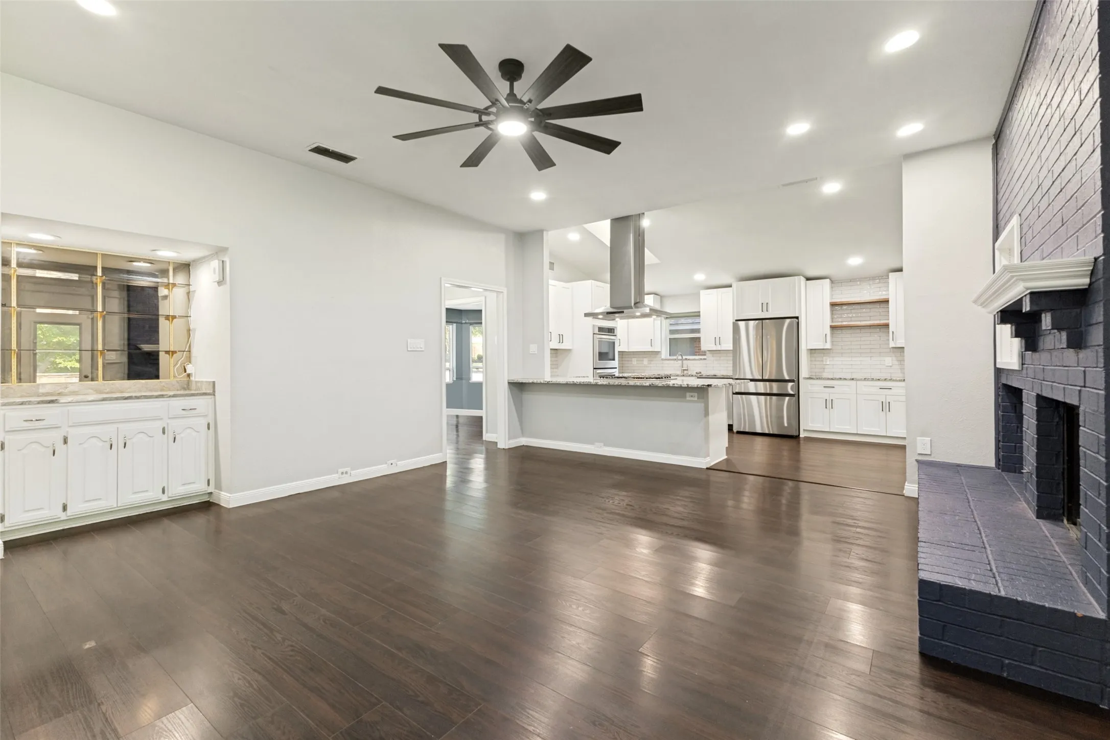 Spacious interior featuring dark wood-finish flooring and a vaulted ceiling with a modern ceiling fan