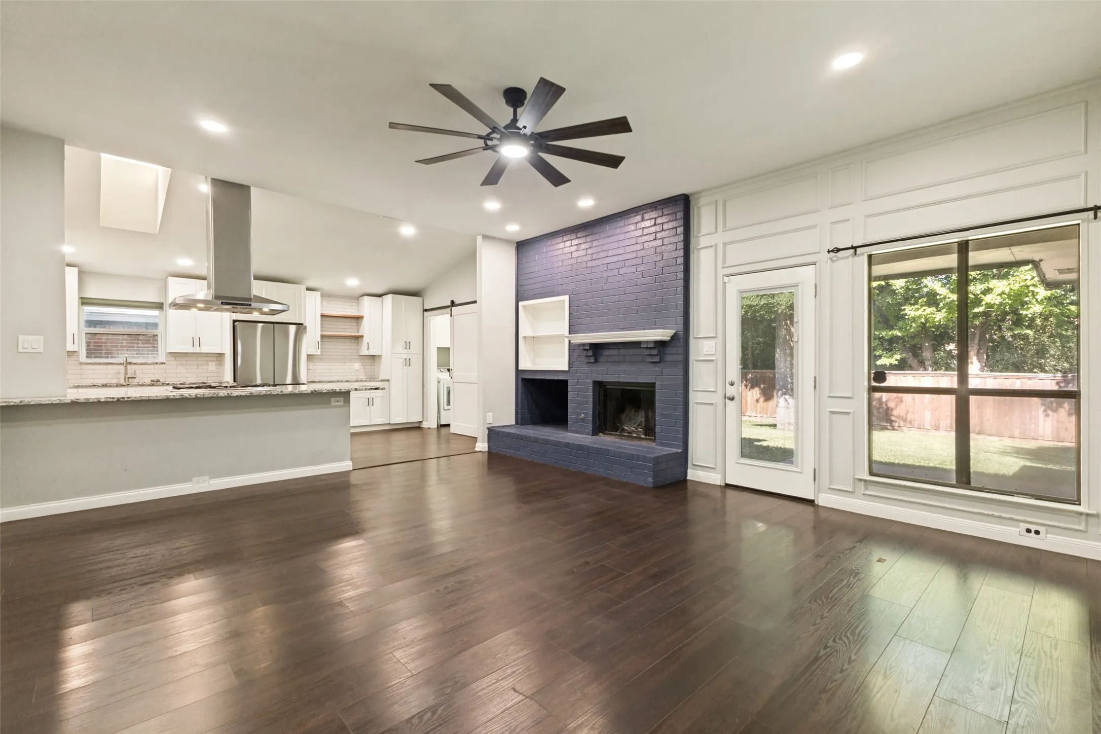 Open-concept living area featuring rich wood-finish flooring, a contemporary ceiling fan, and recessed lighting