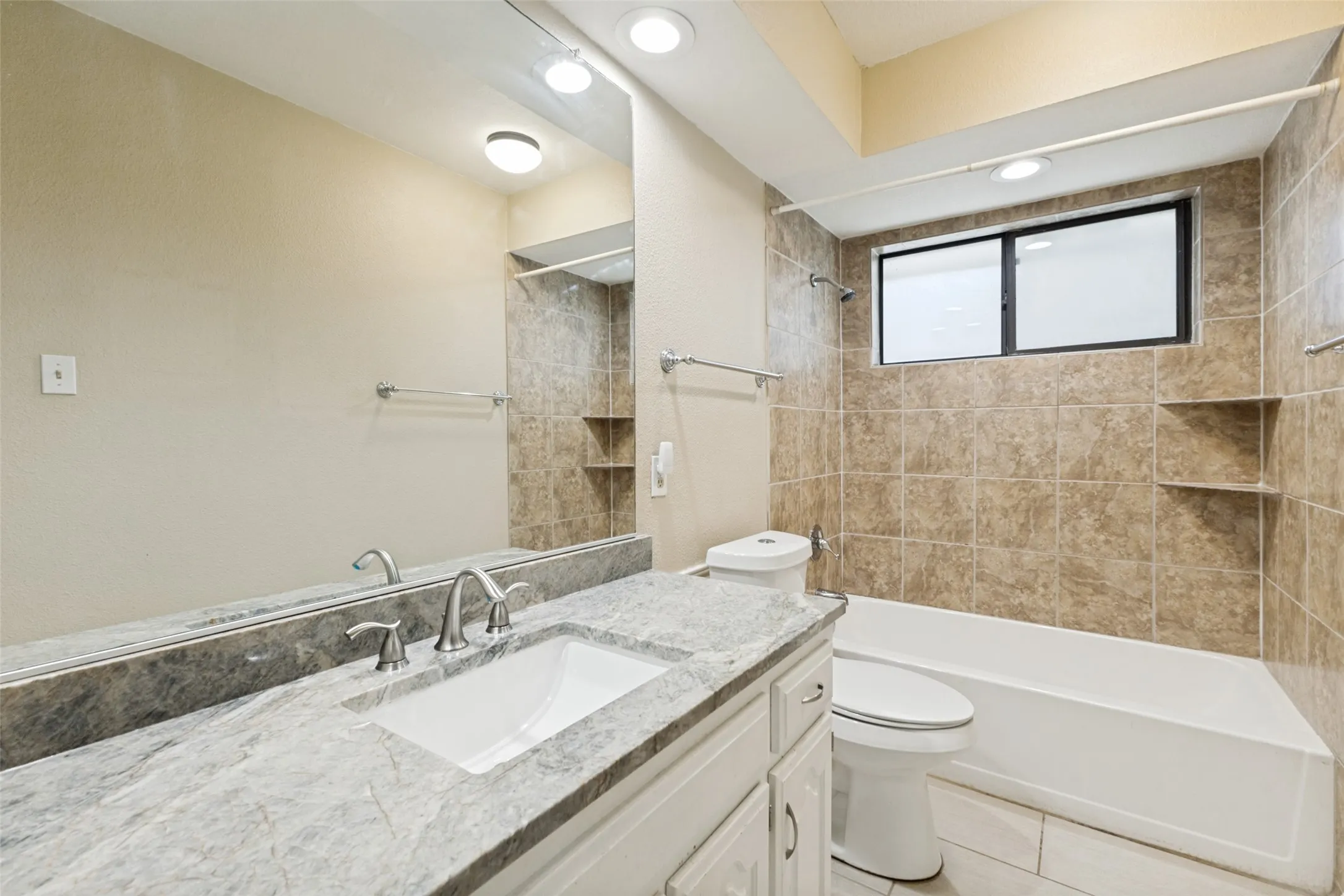 Bathroom featuring a spacious vanity with a light-colored countertop, an undermount sink with a brushed nickel faucet, and a large wall-mounted mirror