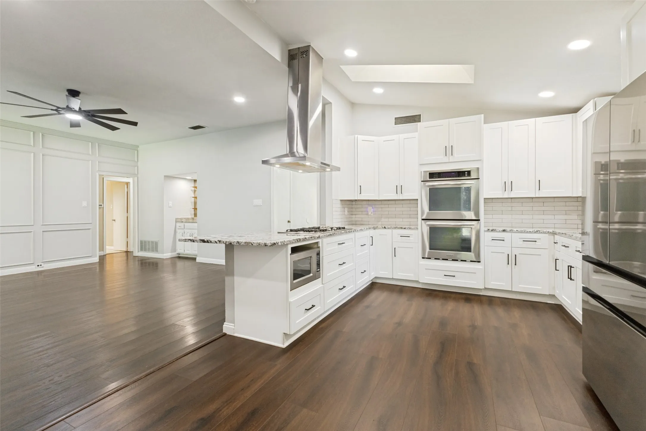 Gourmet kitchen with white cabinetry, stainless steel appliances, and a central island with a built-in microwave