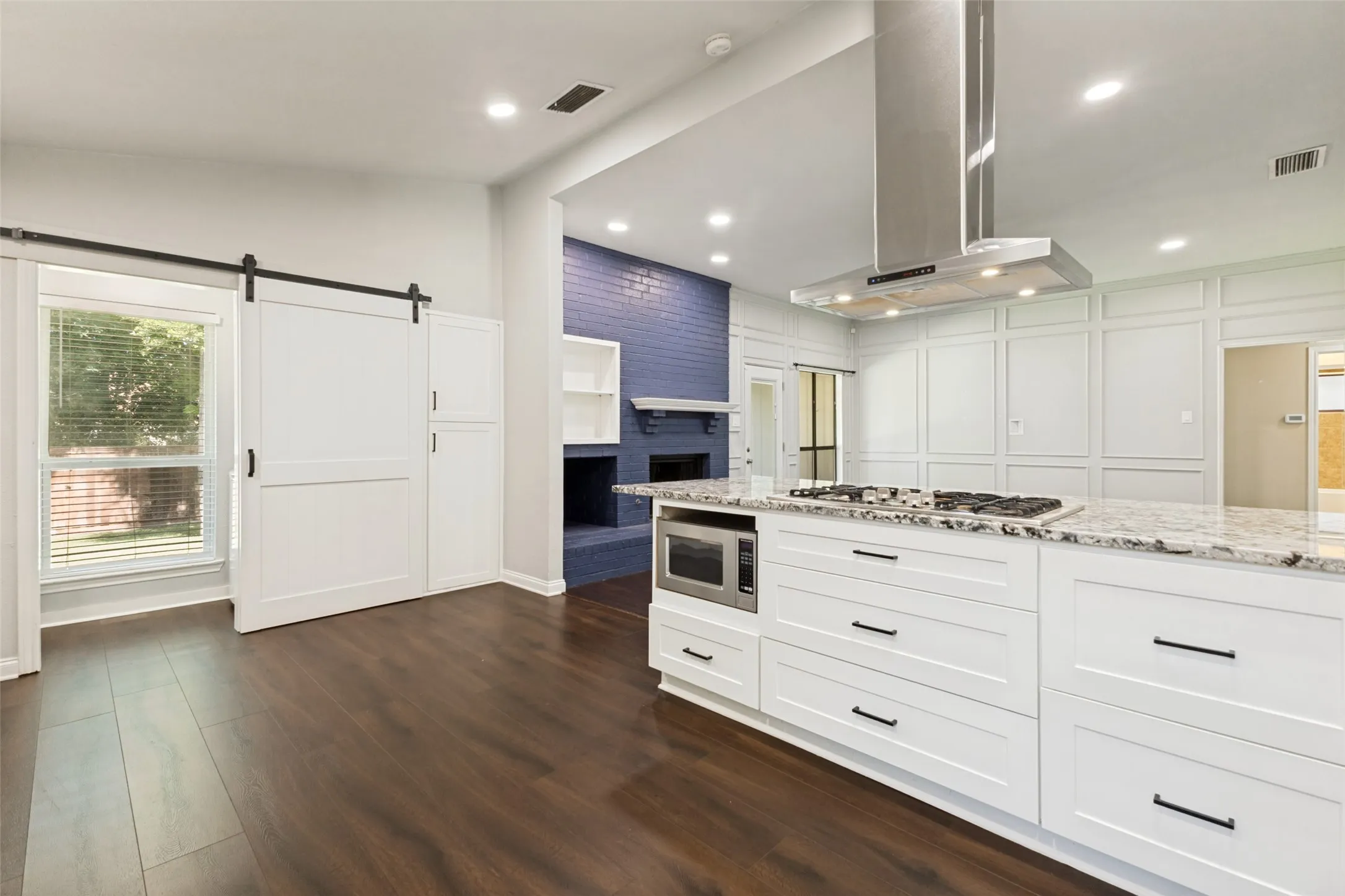 Kitchen featuring a large island with a built-in gas cooktop, granite-look countertop, and white shaker-style cabinetry