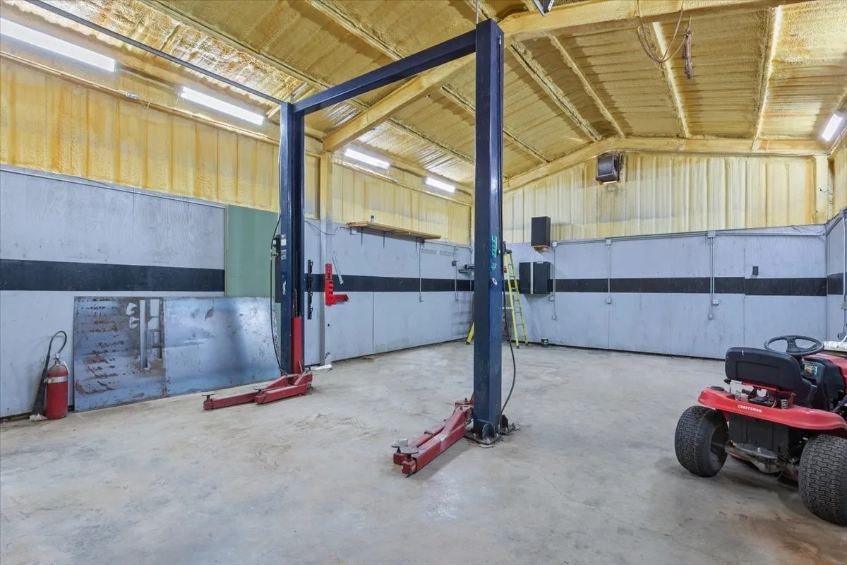 Spacious garage featuring a vehicle lift, concrete flooring, insulated walls, and ceiling-mounted lighting