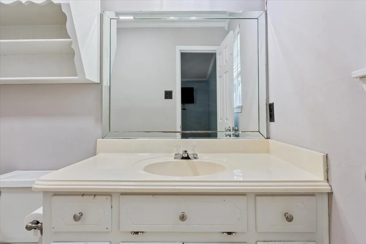 White vanity with integrated sink, chrome faucet, and a large wall-mounted mirror