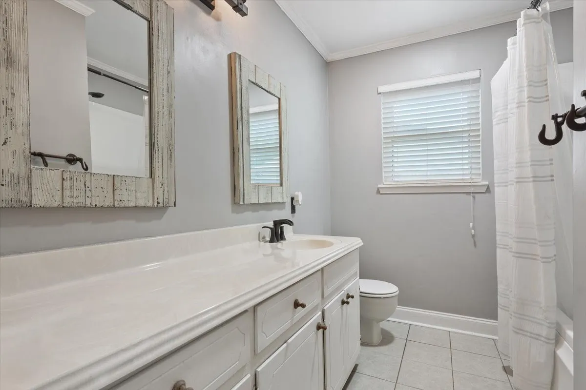 Double vanity featuring integrated sinks, white cabinetry, dark bronze hardware, and coordinating wall-mounted light fixtures