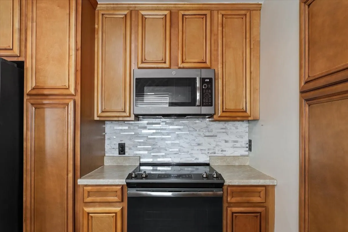 Kitchen station featuring a stainless steel microwave, black electric range, and light-toned countertops