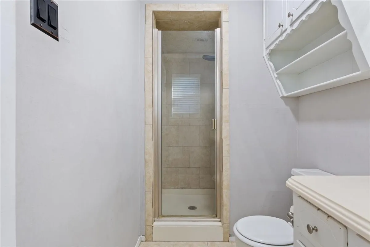 Framed glass shower enclosure featuring a tiled interior and window with blinds
