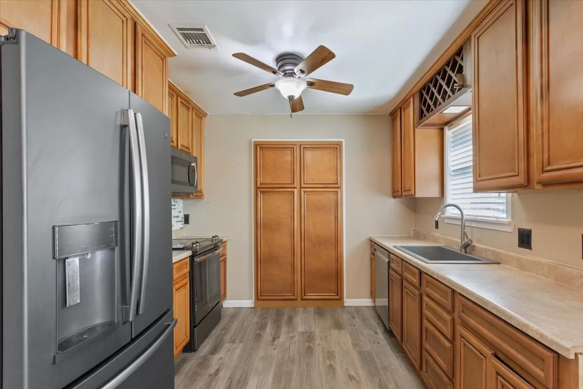 Kitchen featuring wood-finish cabinetry, gray wood-look flooring, and light-colored countertops