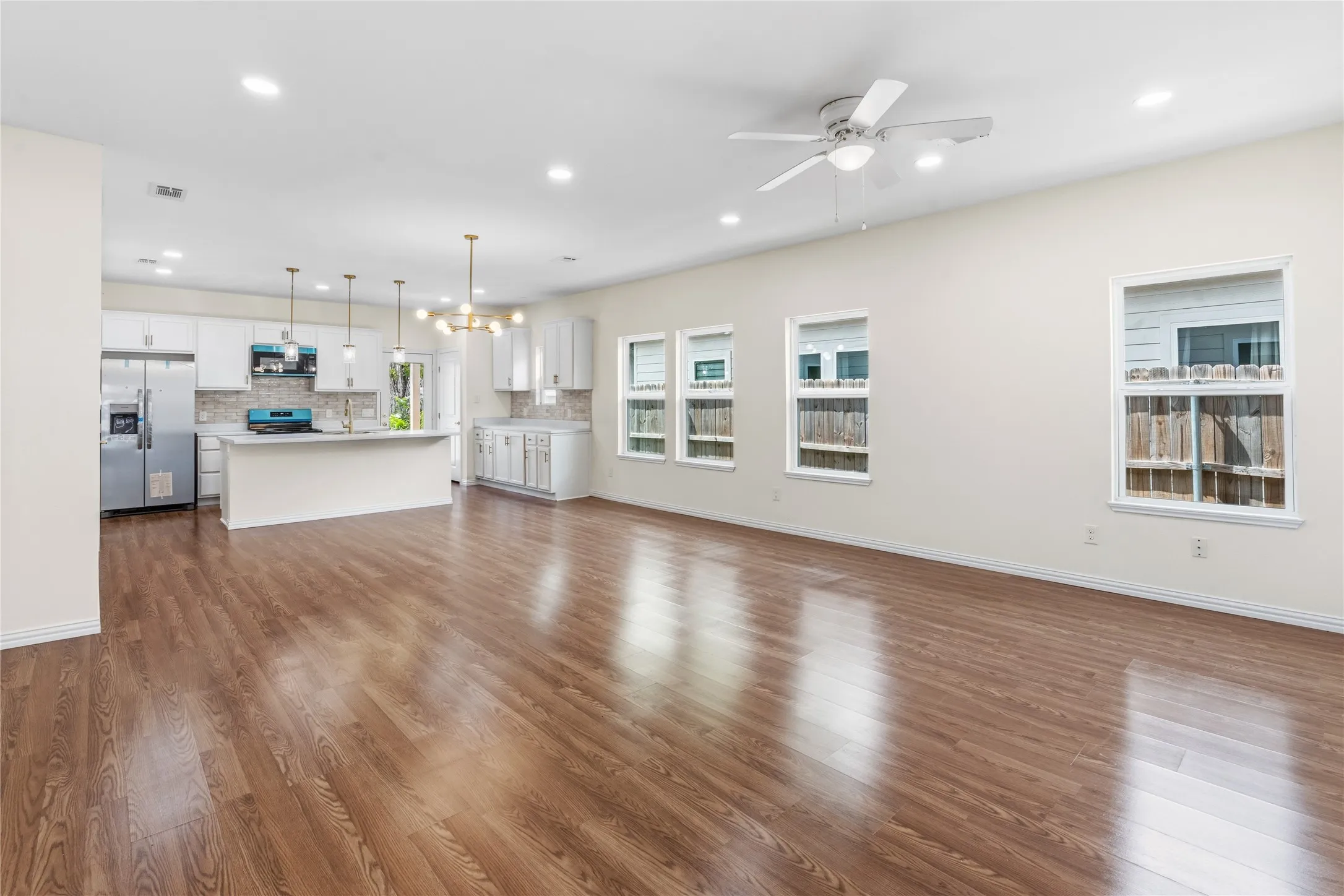 Open-concept living area featuring wood-finish flooring, recessed lighting, and a ceiling fan