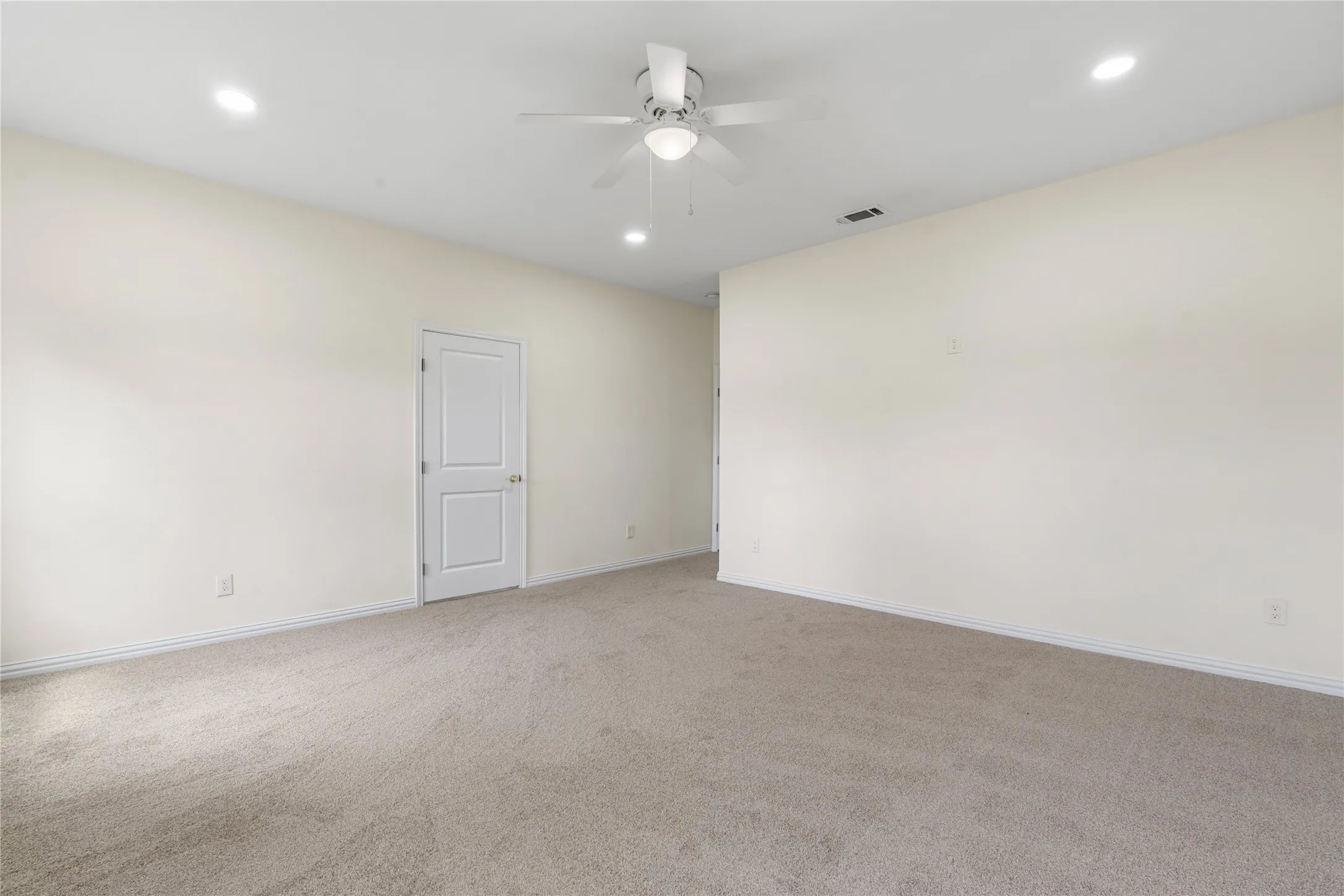 Carpeted room featuring a ceiling fan, recessed lighting, and a paneled interior door