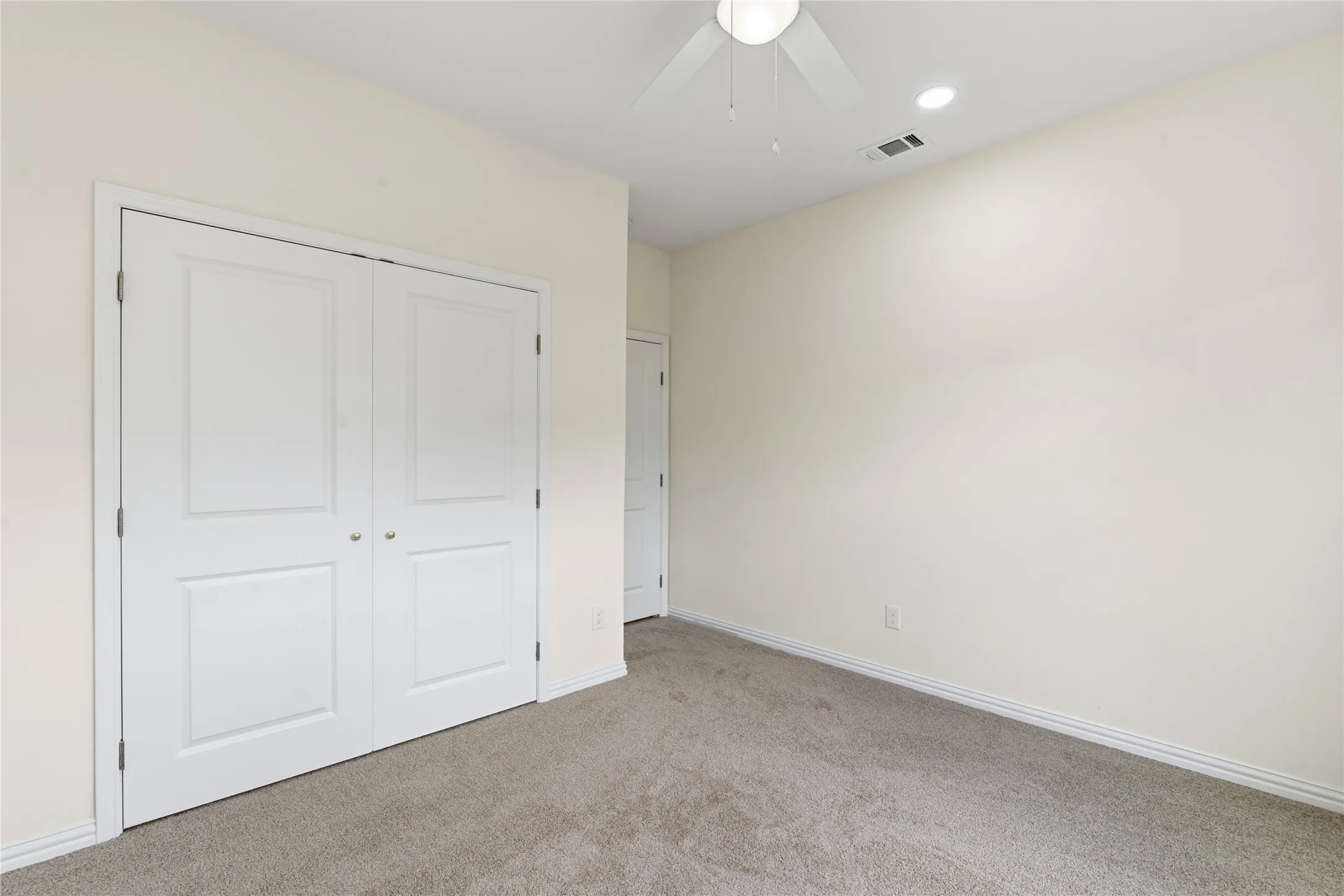 Bedroom featuring light neutral wall paint, carpet flooring, baseboard molding, a ceiling fan, and a double-door closet