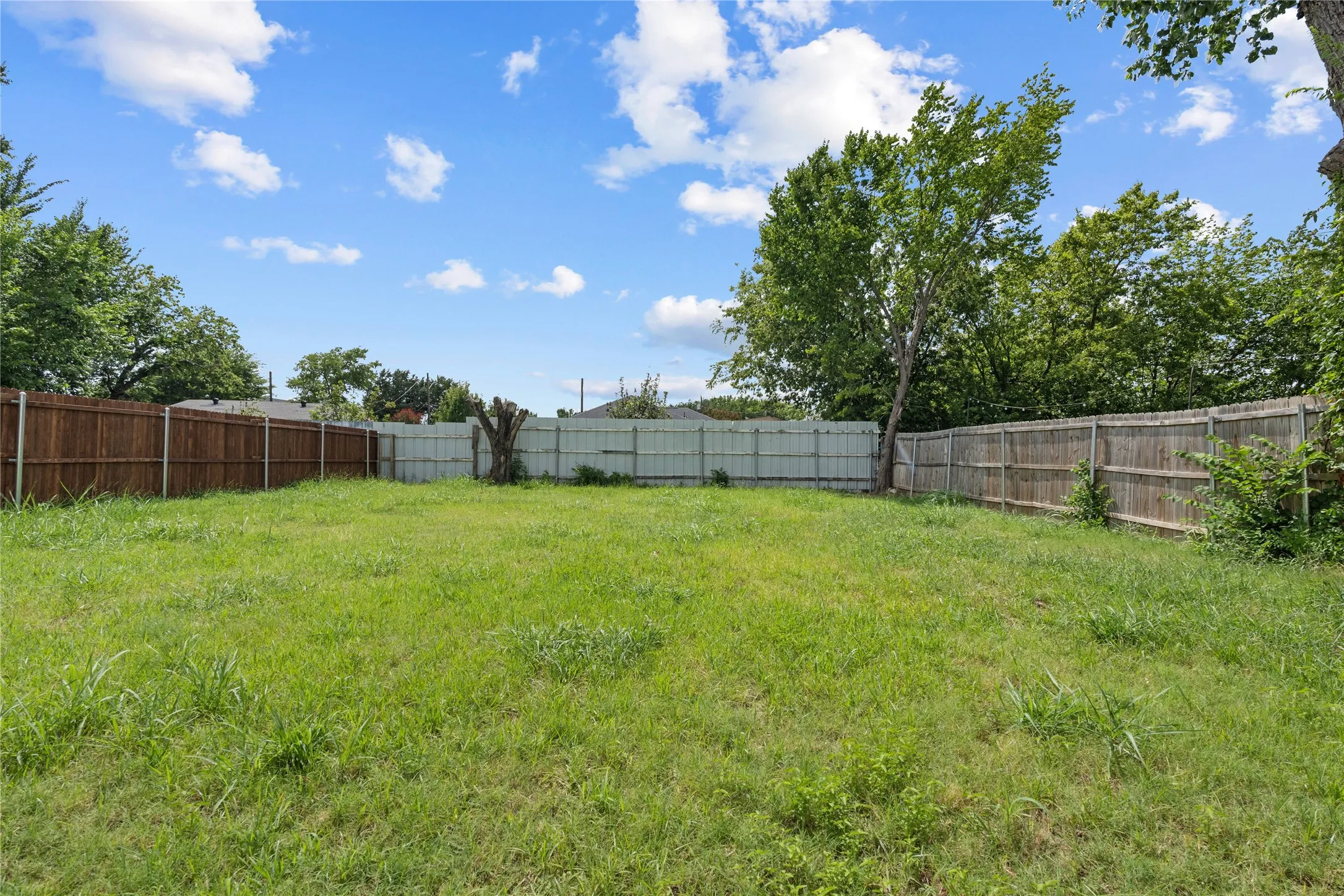 Expansive green lawn with mature trees and a perimeter fence