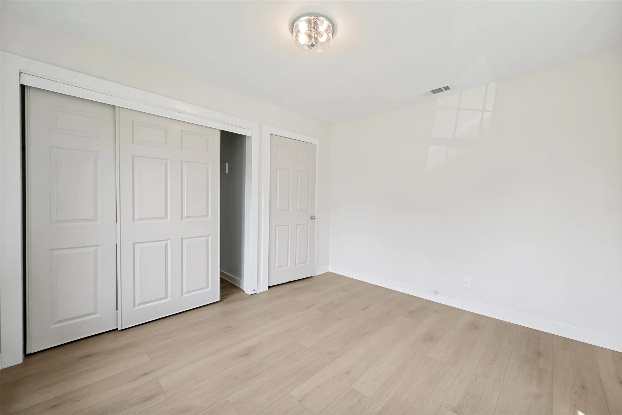 Room with wood-finish flooring, white walls, and a semi-flush mount ceiling light