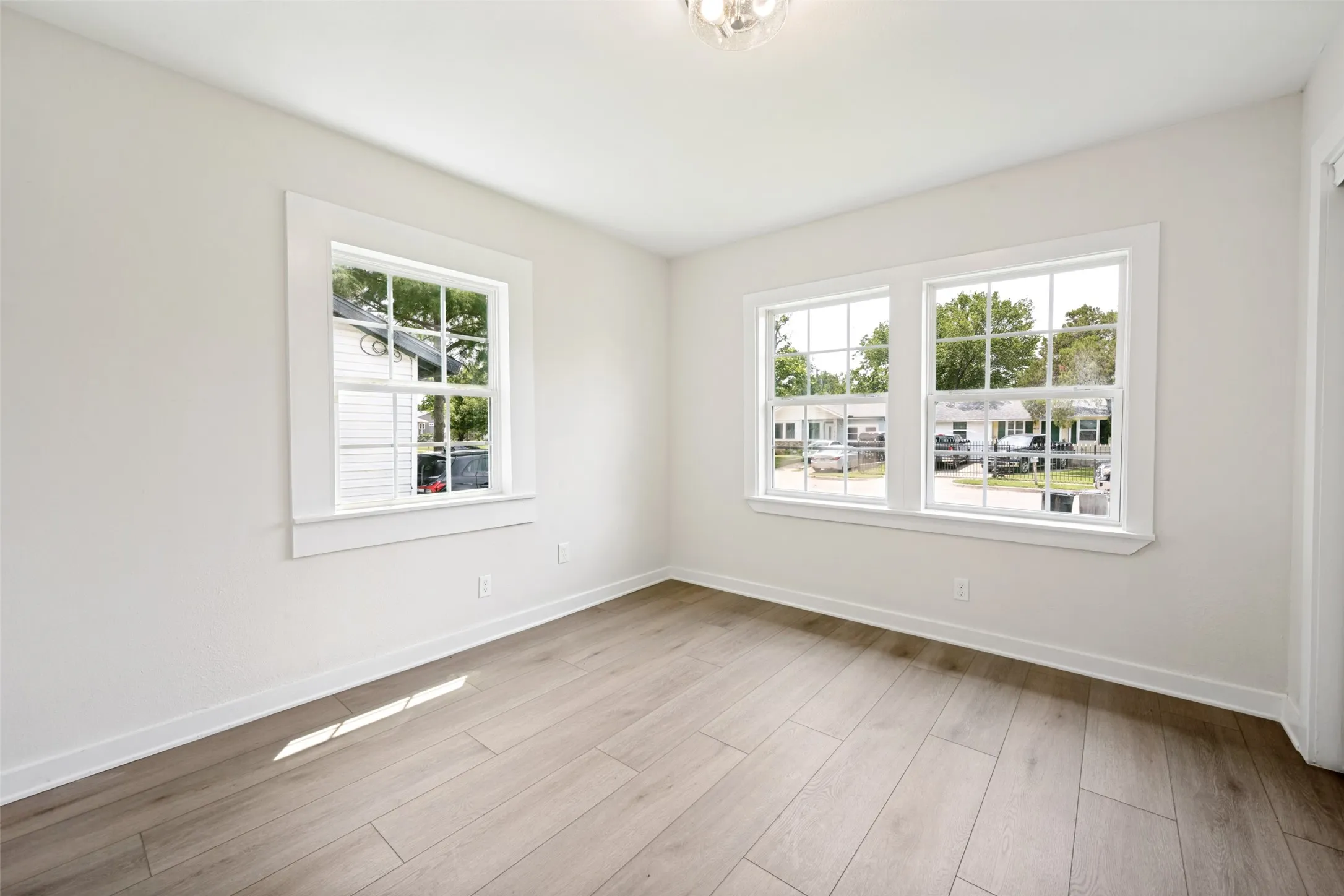 Bright interior space featuring light wood-finish flooring, white baseboards, and crisp white walls