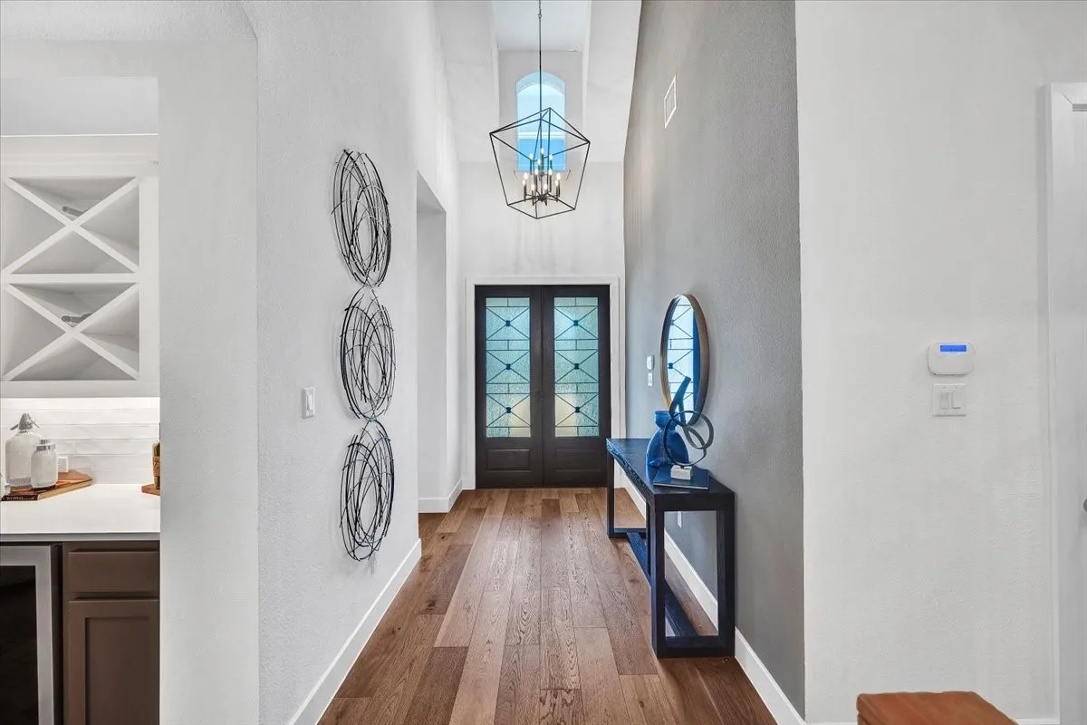 Entryway featuring wood-finish flooring, a tall vaulted ceiling, and a built-in dry bar with a wine rack and subway tile backsplash