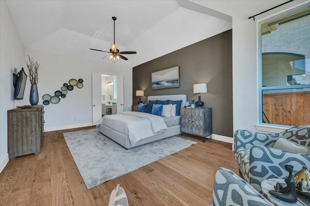 Spacious room featuring vaulted ceilings, wood-finish flooring, and a ceiling fan