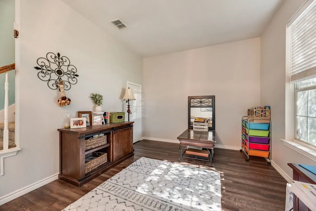 Spacious room featuring wood-finish flooring, light-toned walls, and a large window with blinds