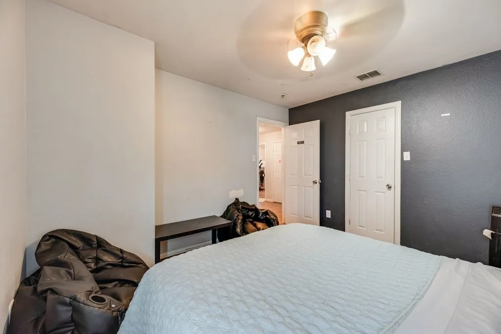 Bedroom featuring a ceiling fan with light kit, textured walls, and two paneled doors