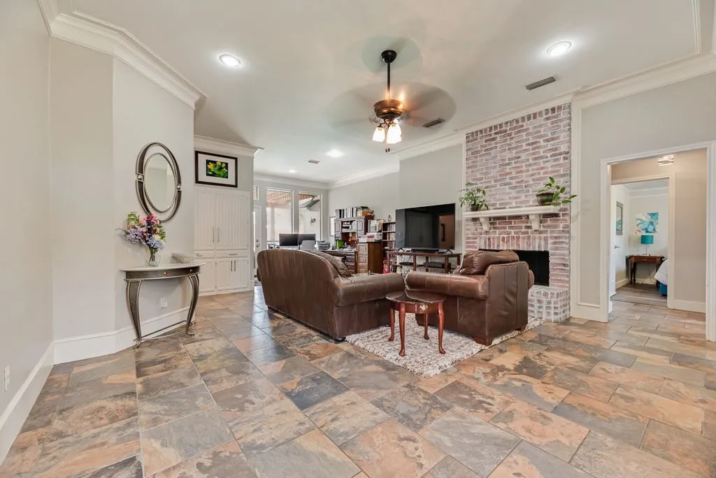 Spacious living area featuring multi-tone tile flooring, a painted brick fireplace with hearth and mantel, and built-in cabinetry