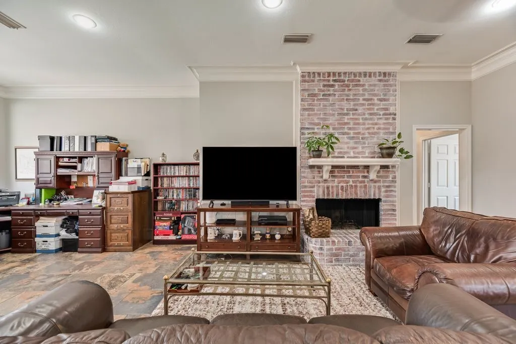 Living room featuring a brick-surround fireplace with a white mantel, light gray walls, and recessed lighting